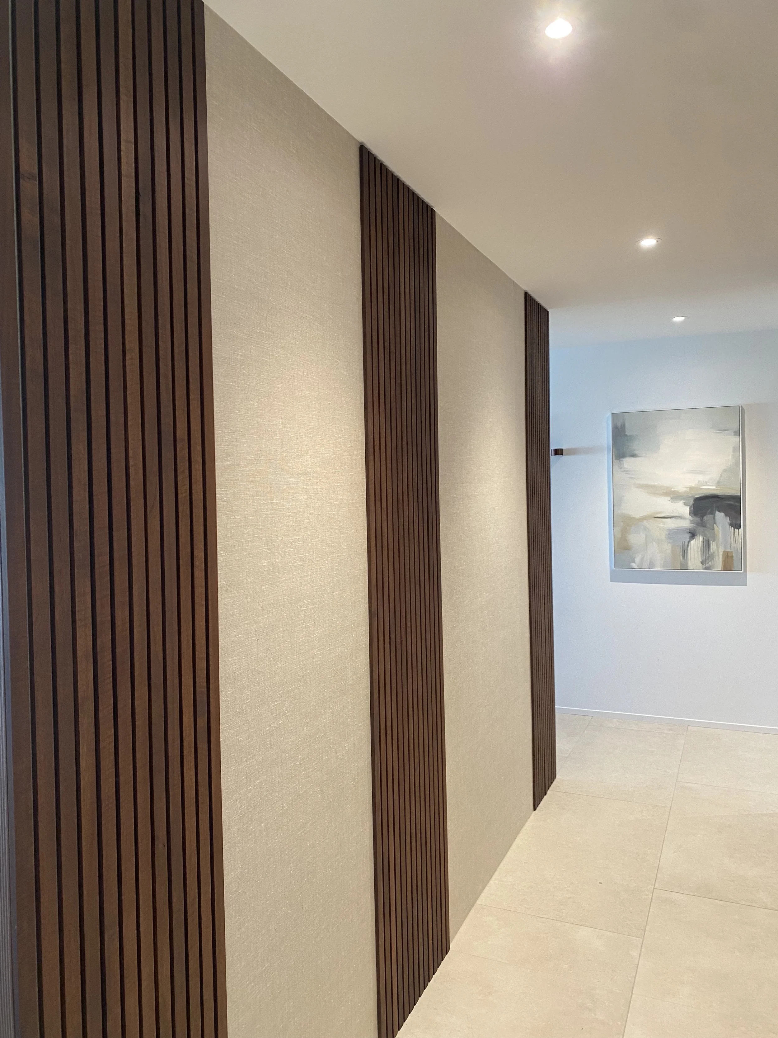 Innenraum mit Wandpaneelen aus dunklem Holz und einer neutralen Wand mit abstraktem Gemälde.