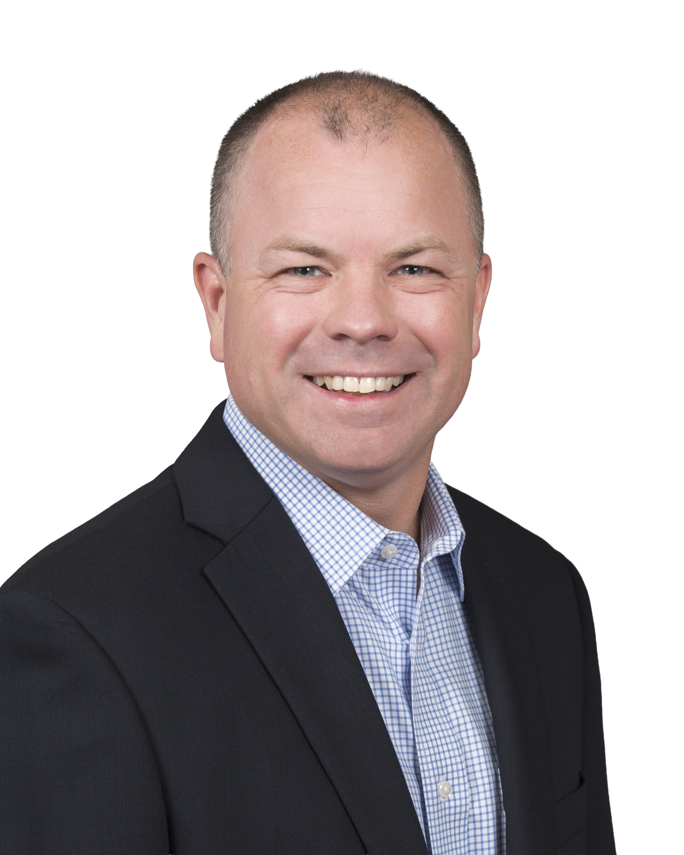 A smiling man with short brown hair wearing a checkered dress shirt.
