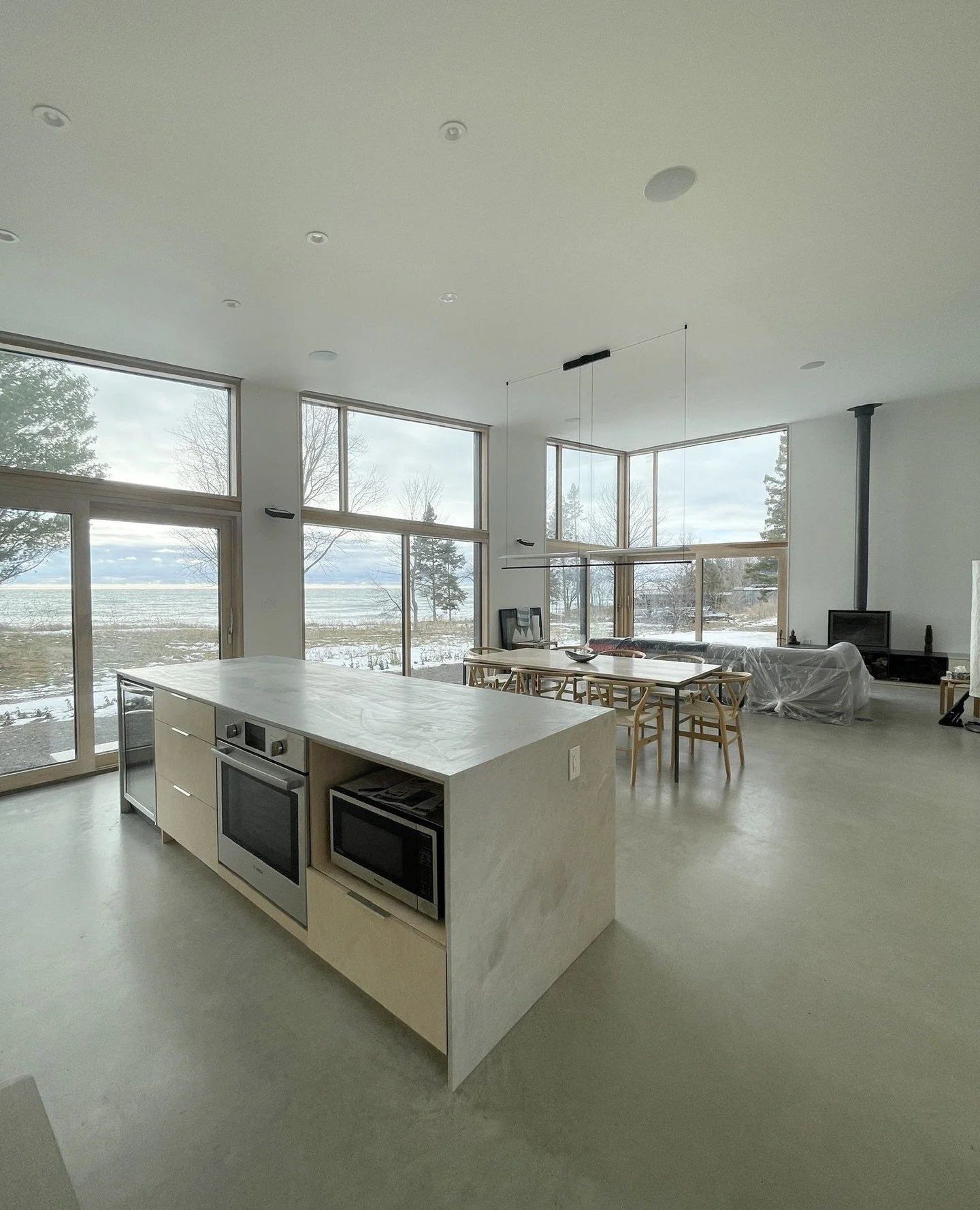 ✨ Modern design meets nature ✨ This open-concept kitchen and dining space maximizes light, clean lines, and the stunning waterfront views. Every detail, from the sleek island to the expansive windows, is crafted for sunlight and style. #ModernHome #L