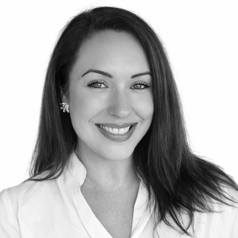 Black-and-white portrait of a woman with short dark hair, wearing a light-colored blazer, looking directly at the camera with a slight smile.