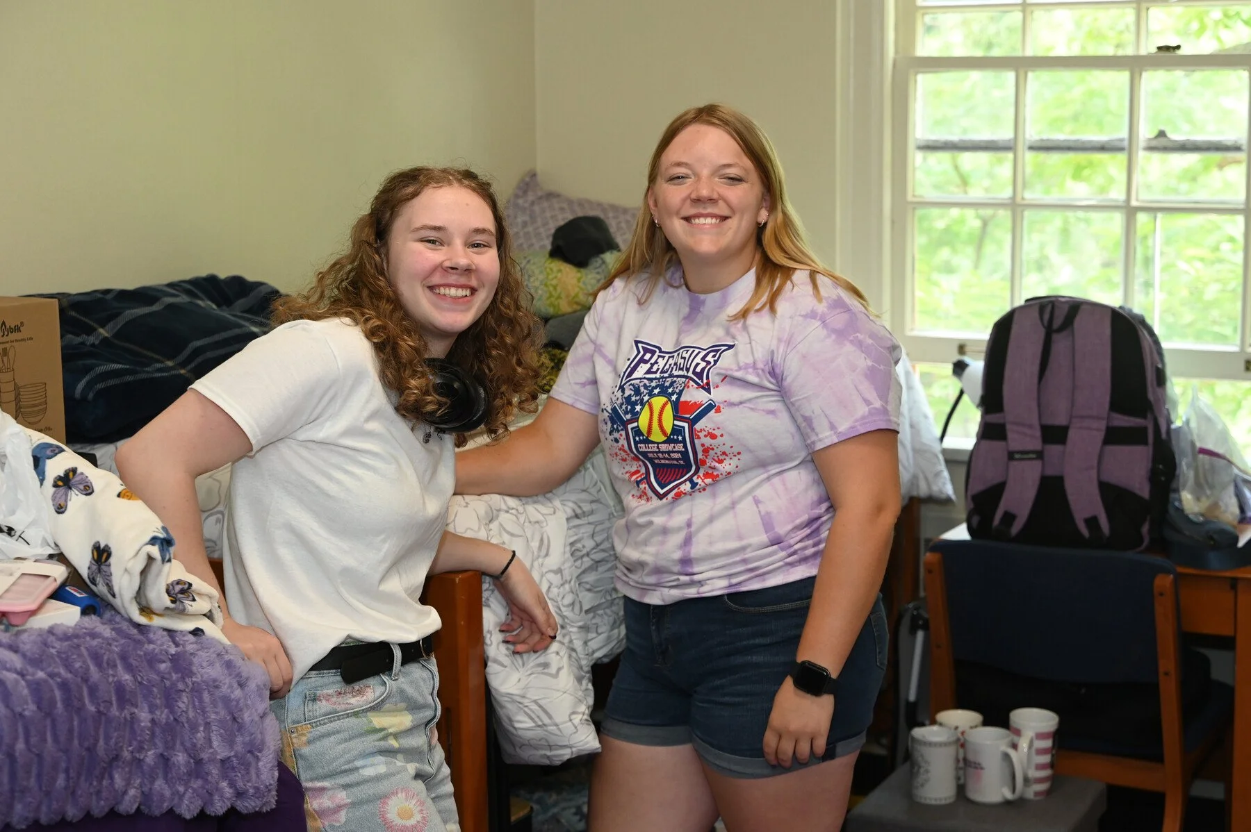 Two new roommates smile together in their dorm room