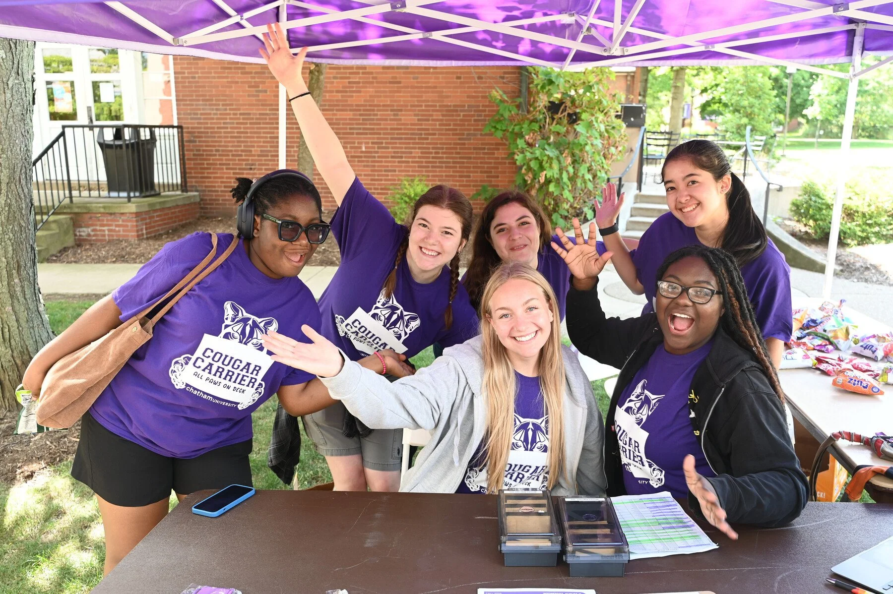 A group of Chatham University volunteers posing for a silly photo at a Move-In Day tent