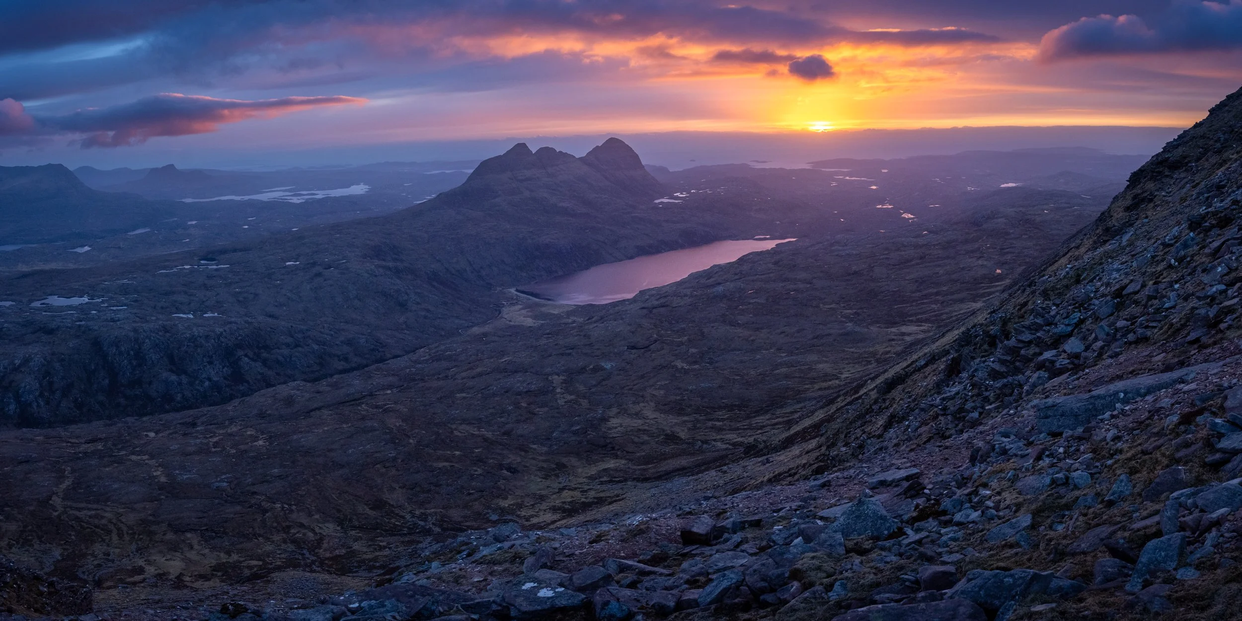 A landscape photograph of Suilven in Assynt, in the Northwest Highlands of Scotland, taken from the summit of Canisp during a spectacular sunset.
