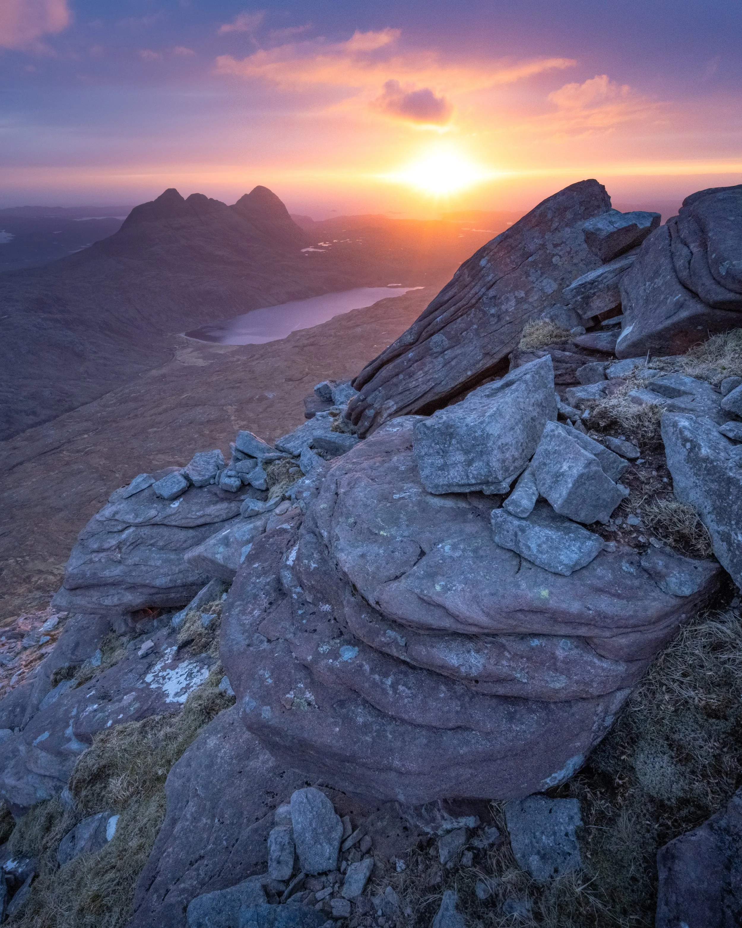 A landscape photograph of Suilven in Assynt, in the Northwest Highlands of Scotland, taken from the summit of Canisp during a spectacular sunset.
