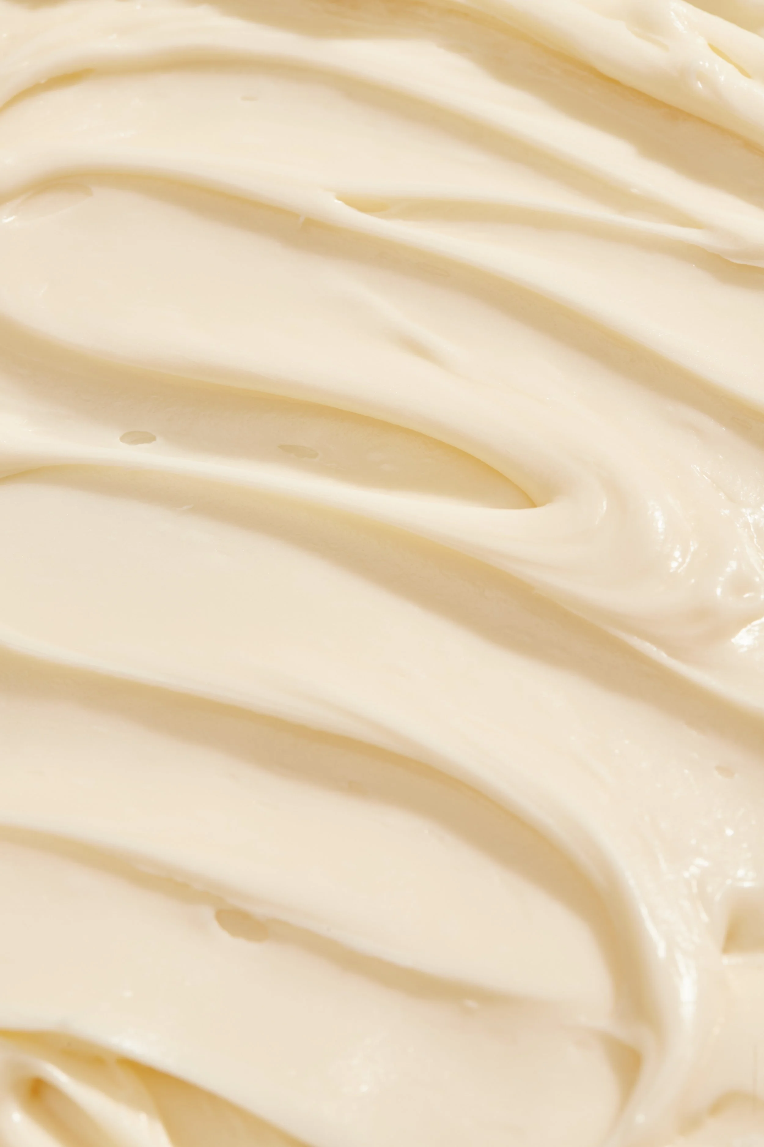 Close-up of creamy, smooth, white frosting or icing with a glossy texture.