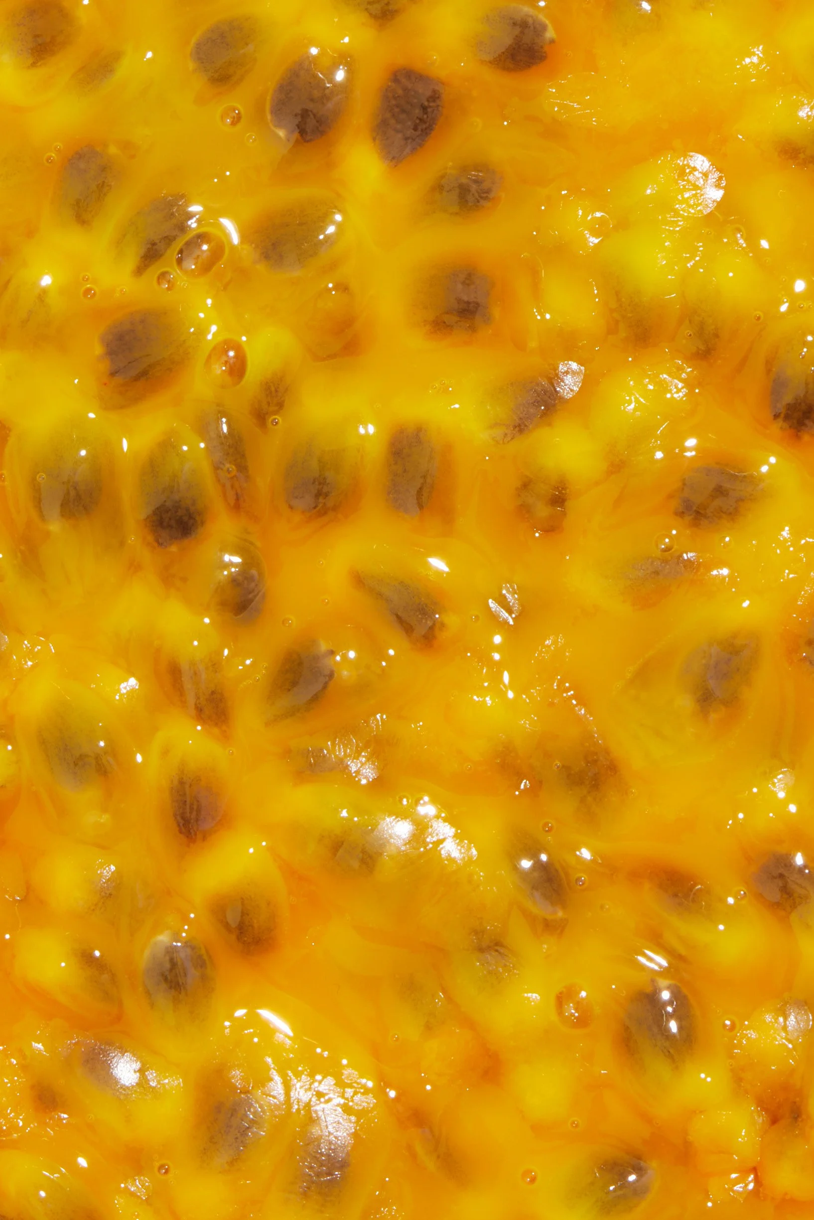 Close-up of passion fruit pulp with black seeds and yellow-orange juice.