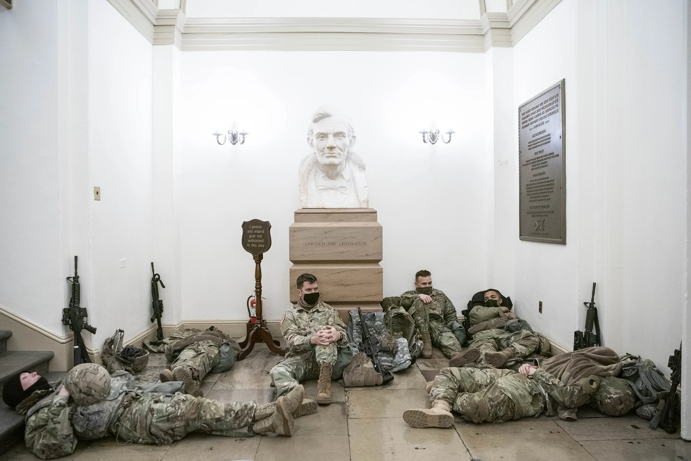(photo by Sarah Silbiger) Washington, D.C., Jan. 13, 2021: National Guard members rest in front of a statue of Abraham Lincoln at the U.S. Capitol in the early morning. Over 26,000 troops were deployed to the city following the January 6th attack.