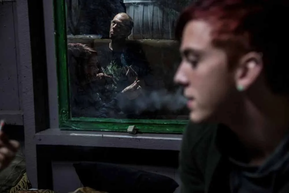 (photo by Toya Sarno Jordan) Eldon, Mo., Sept. 27, 2017: Chelsea, 18, Chris, 32, and Billy, 17, smoke cigarettes at Chris' home. With a 79% child poverty rate, Eldon’s cycles of addiction and poverty raise odds of teens becoming long-term drug users.