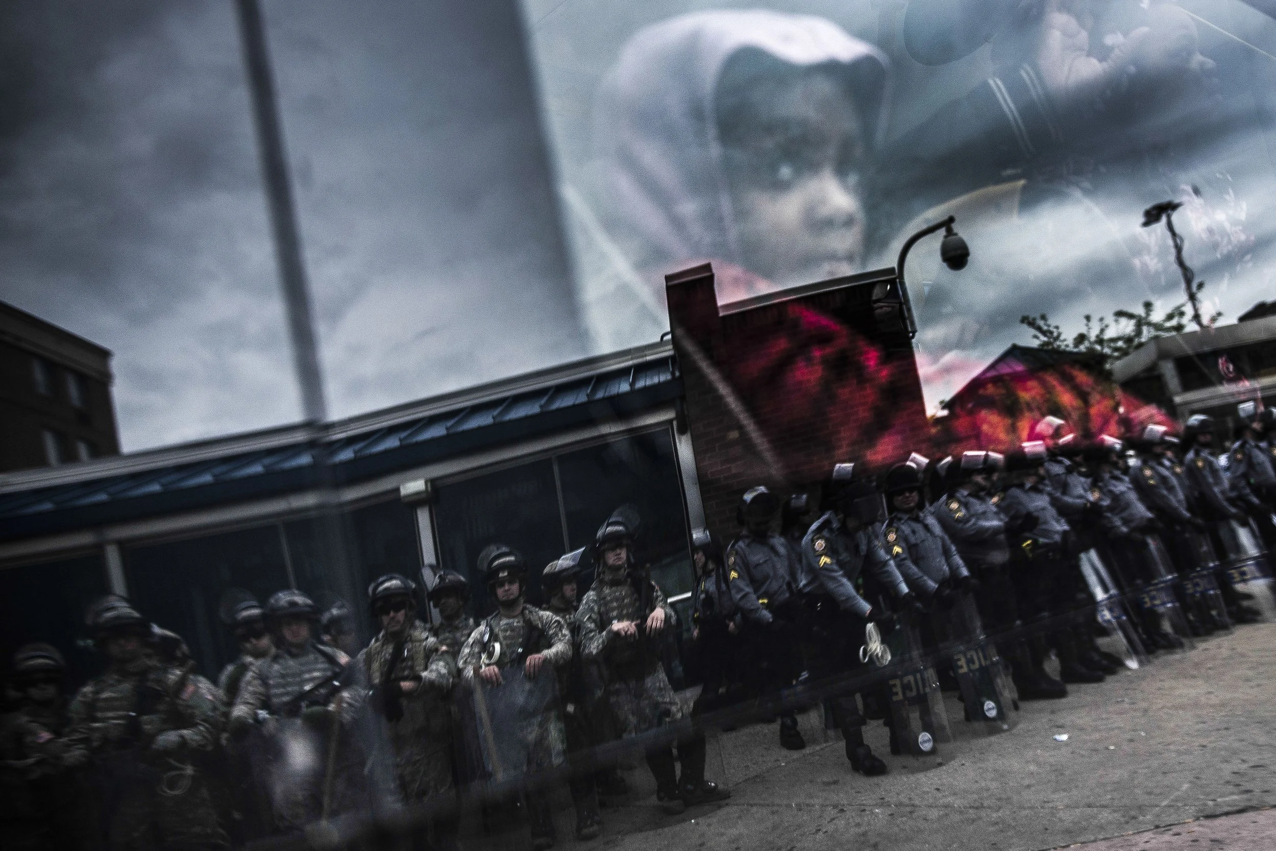 (photo by Gabriella Demczuk) Baltimore, Md., May 1, 2015: A child watches National Guard troops and police during the 2015 Baltimore protests following the death of Freddie Gray in police custody.