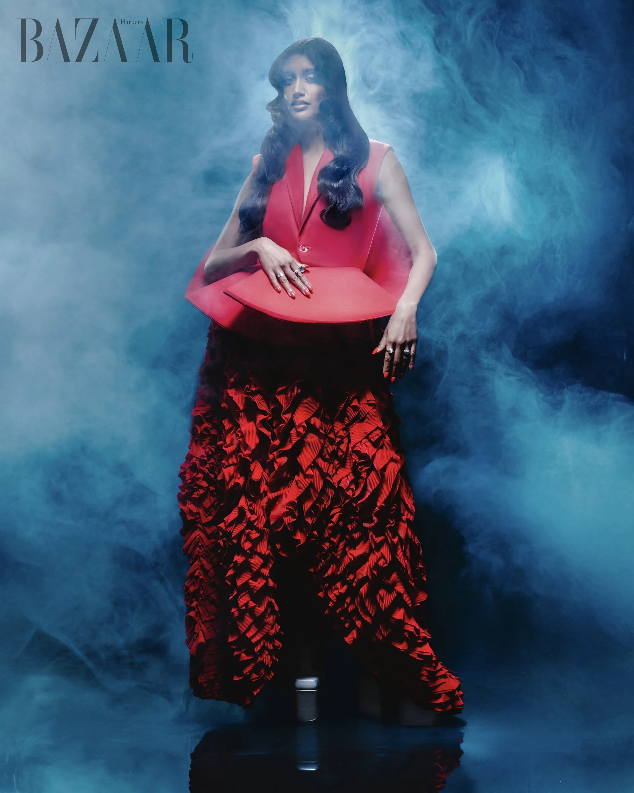 Harpers Bazaar editorial portrait featuring model in sculptural red dress surrounded by blue smoke photographed by Radhika Muthanna