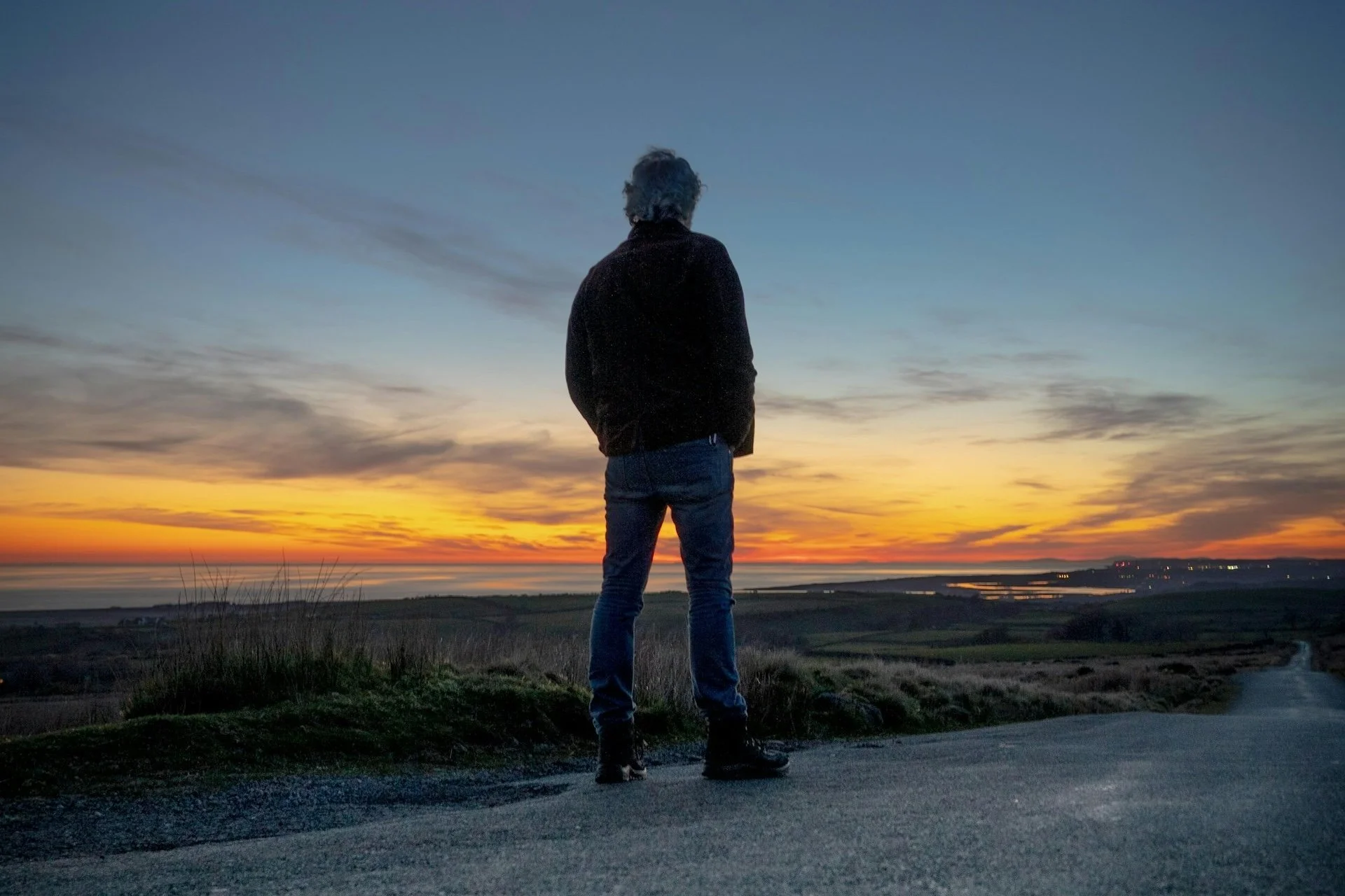 A man looking out overlooking a field and a road into the city