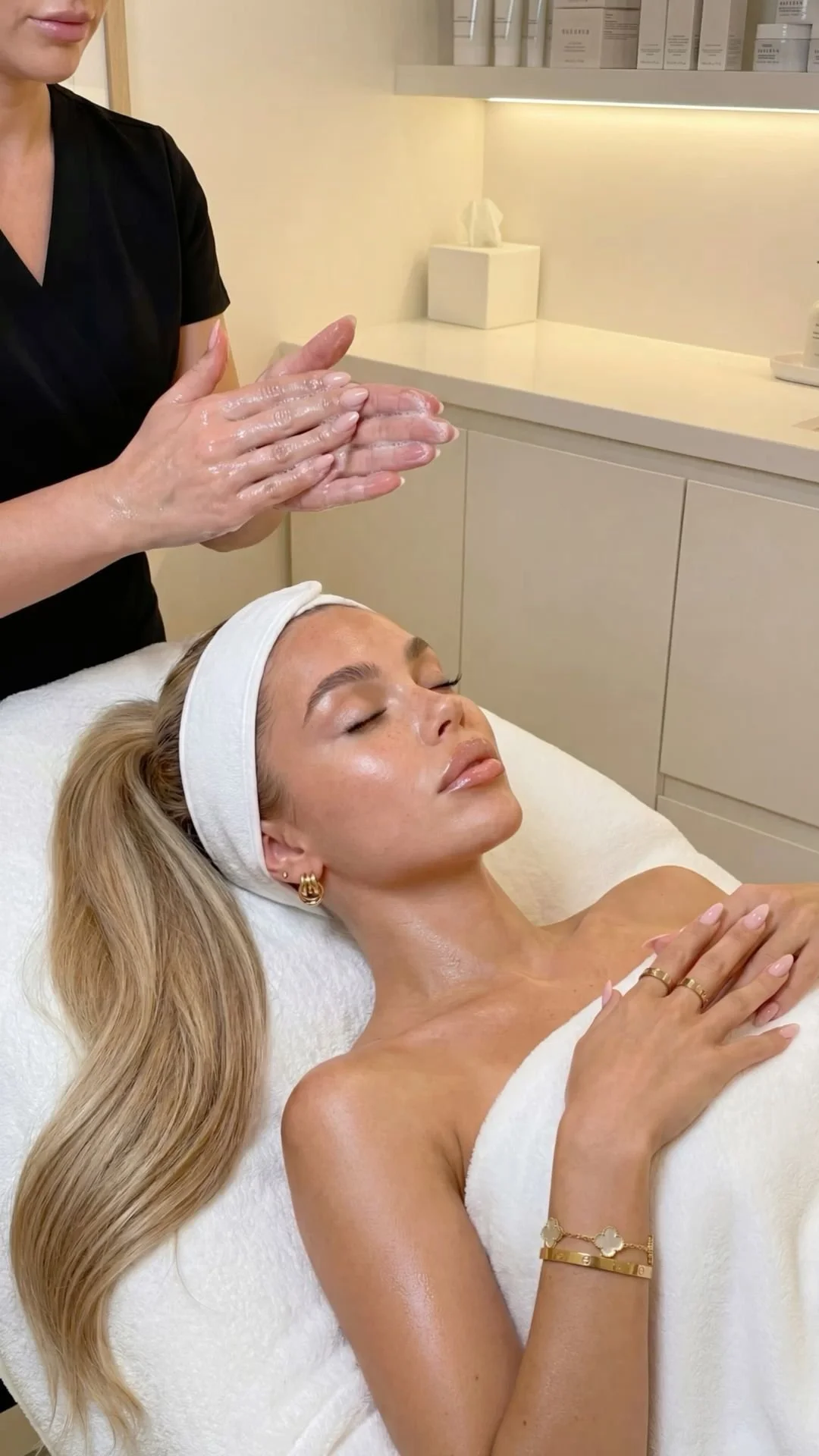 A woman lying down receives skincare from a professional.