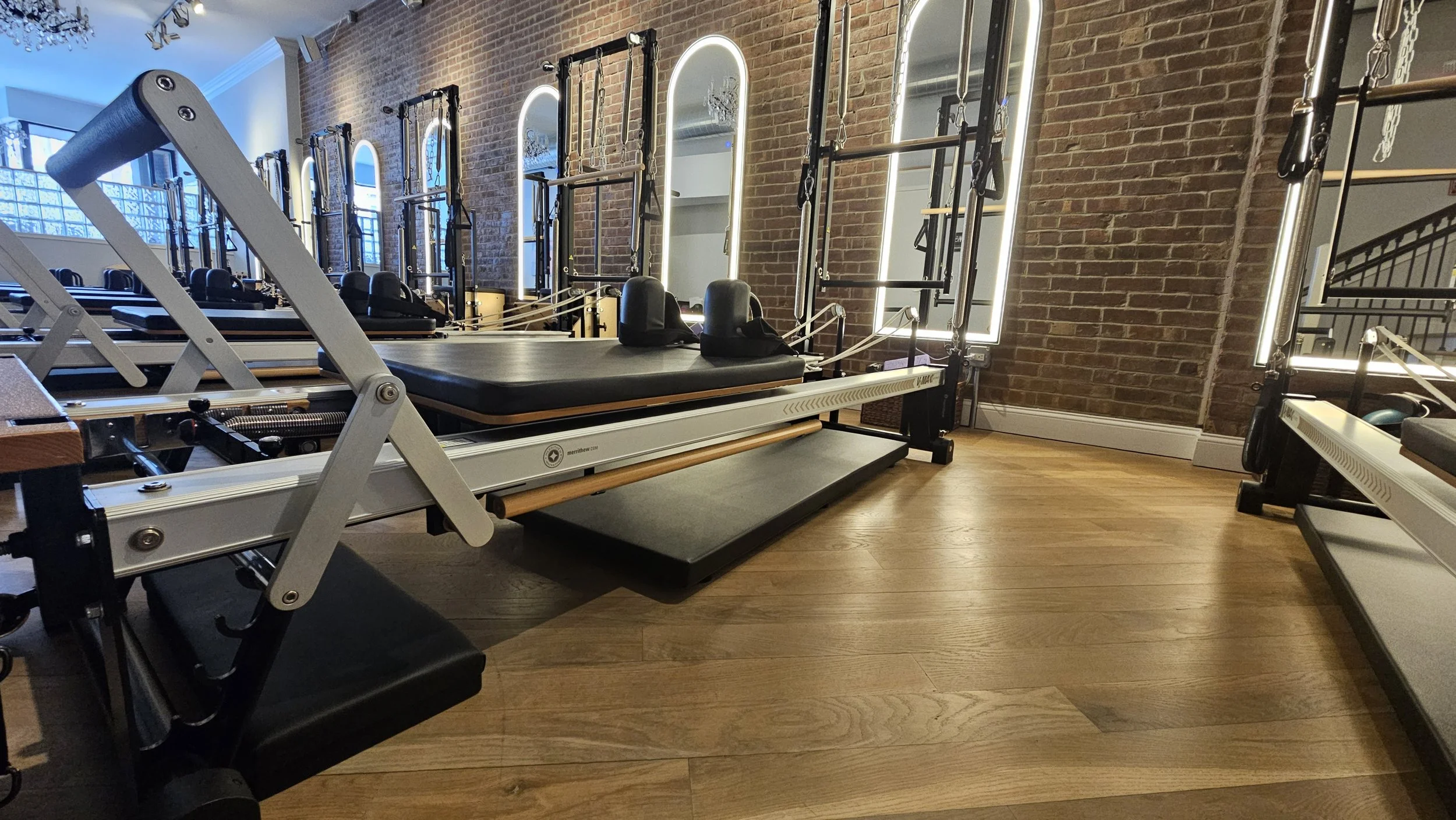 Pilates reformer machine , springs, bars, and straps in a Pilates studio with brick walls and wooden flooring in Red Bank NJ