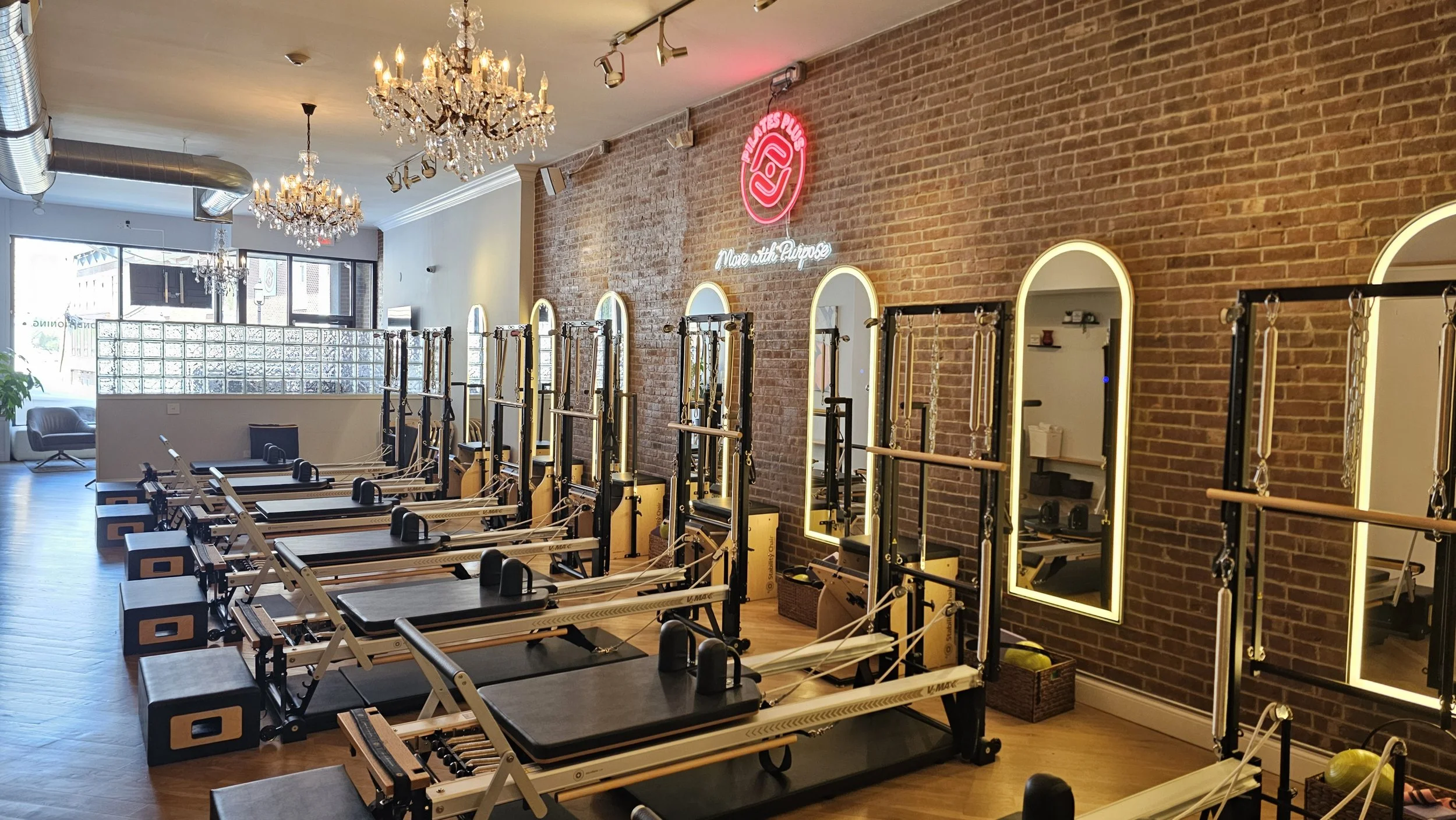 Pilates Plus Red Bank studio with reformers and the Pilates Plus logo