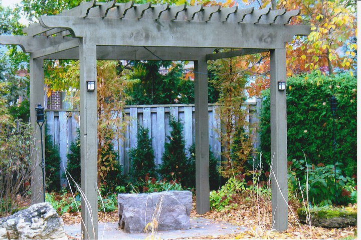 Wooden pergola in a garden with rock and plants