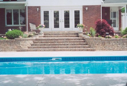 Outdoor swimming pool with steps leading to a brick house