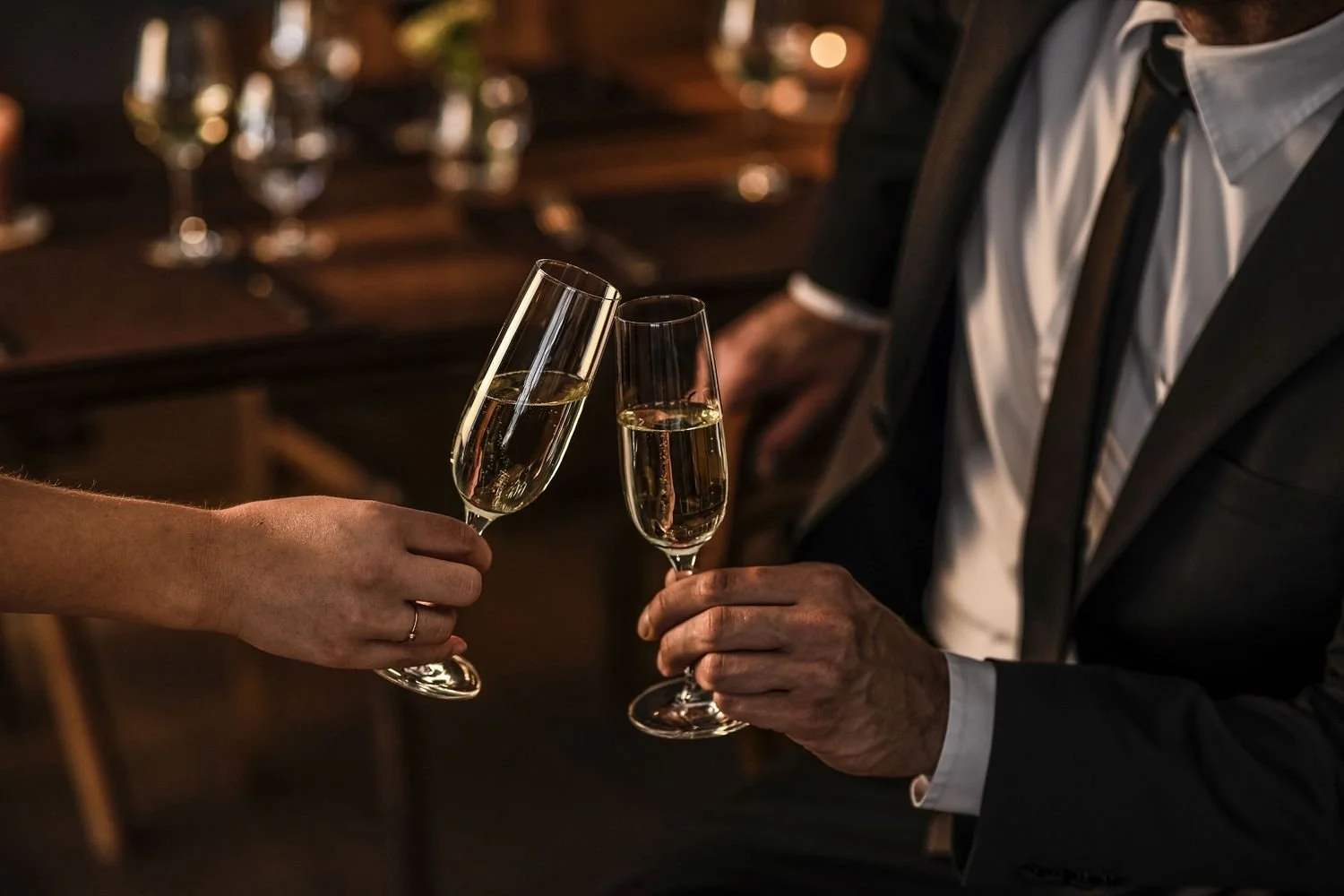 Two people toasting with champagne glasses in a dimly lit setting.