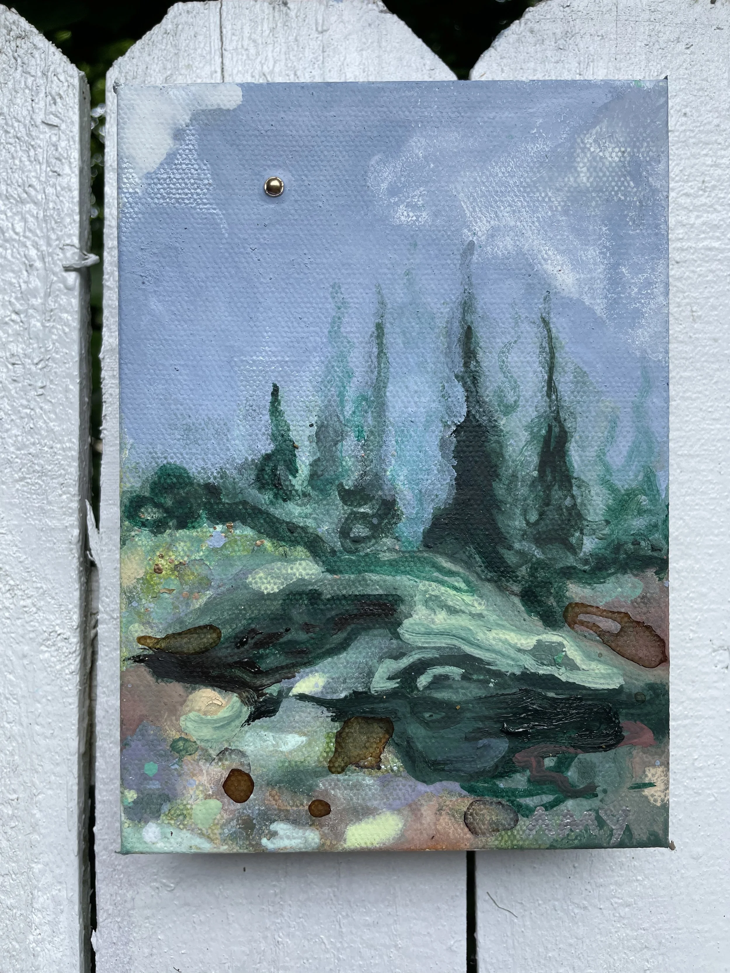 Small abstract painting with green, black, and brown brushstrokes on a blue-gray background, attached to a white wooden fence.