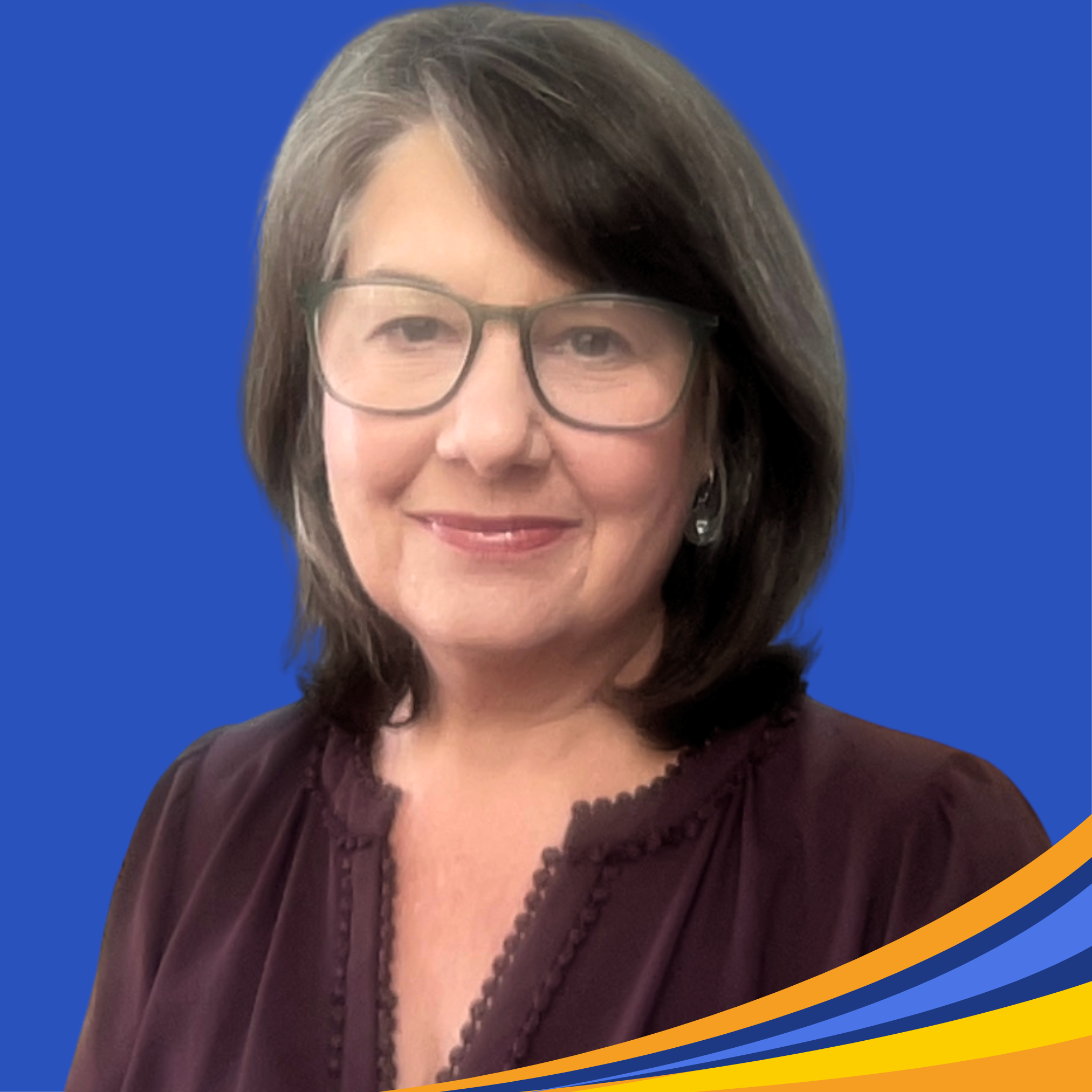 smiling woman with dark purple shirt, brown shoulder length hair and green glasses