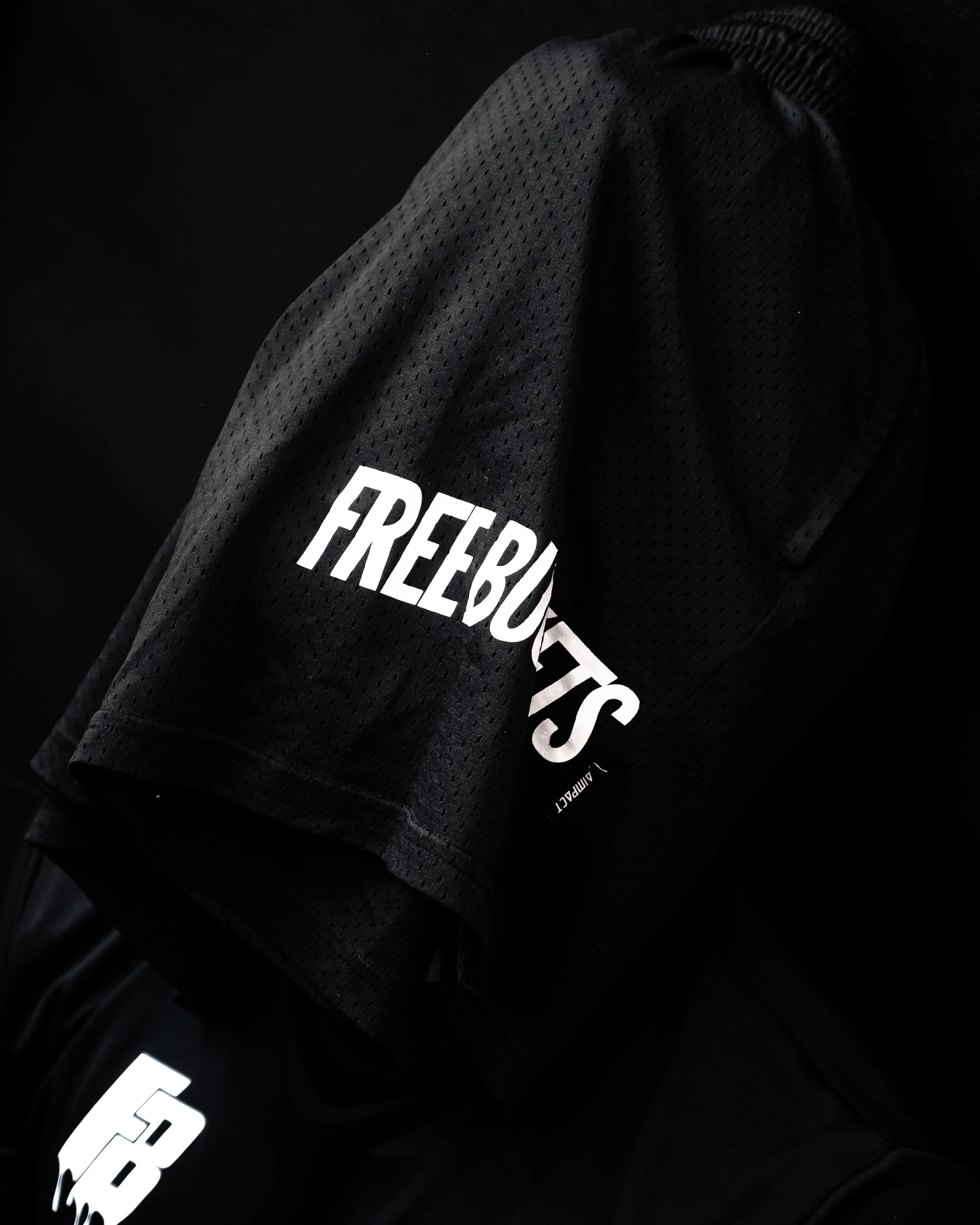 Close-up of black athletic gloves with white text, showing textured fabric and part of a black jacket.