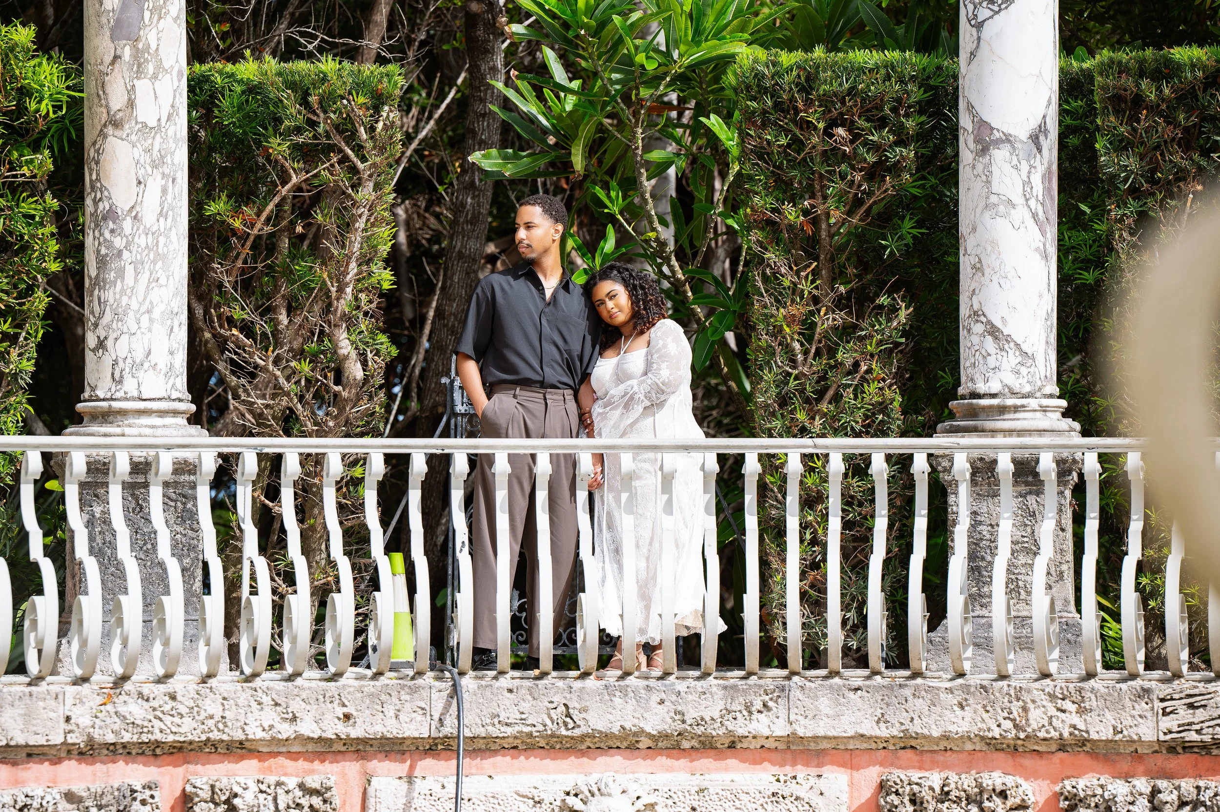 A couple embracing outdoors, with the man gently holding the woman's face and their noses touching, eyes closed, in a tender moment.