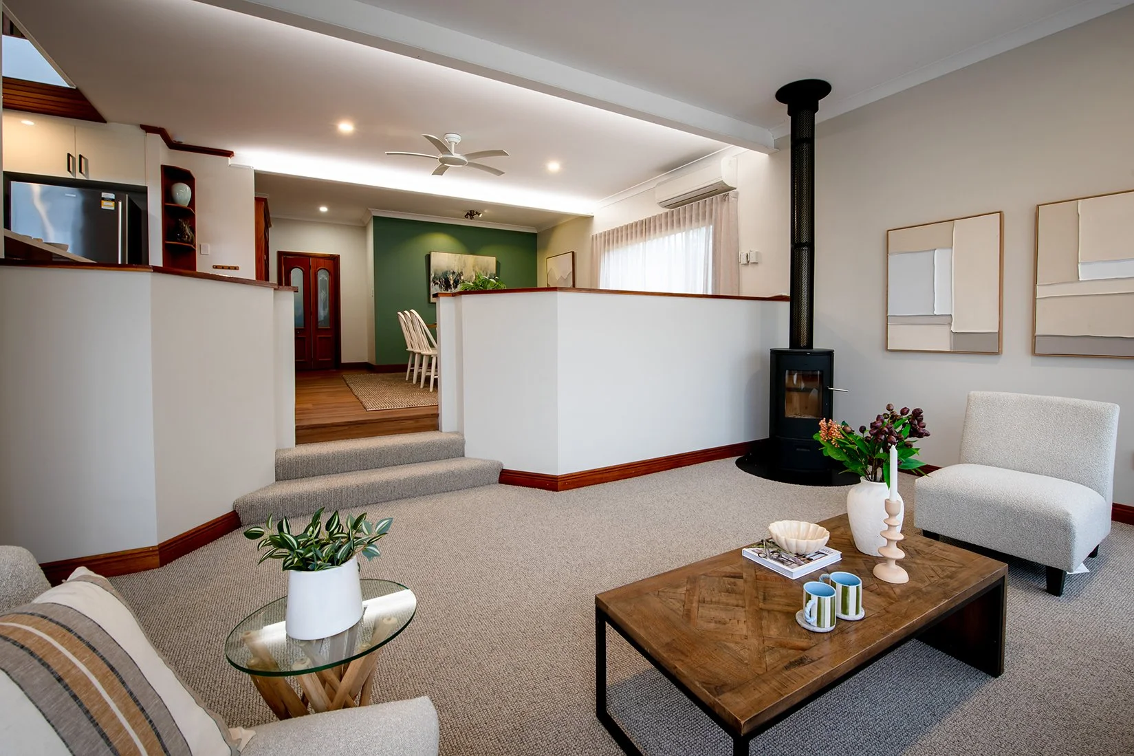 A cosy living area with carpet, a coffee table and rugs, centred around a fireplace