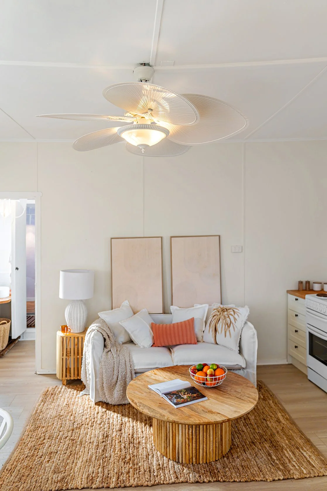 Bright beach‑inspired living room with palm‑print wallpaper, soft lighting, and coastal styling