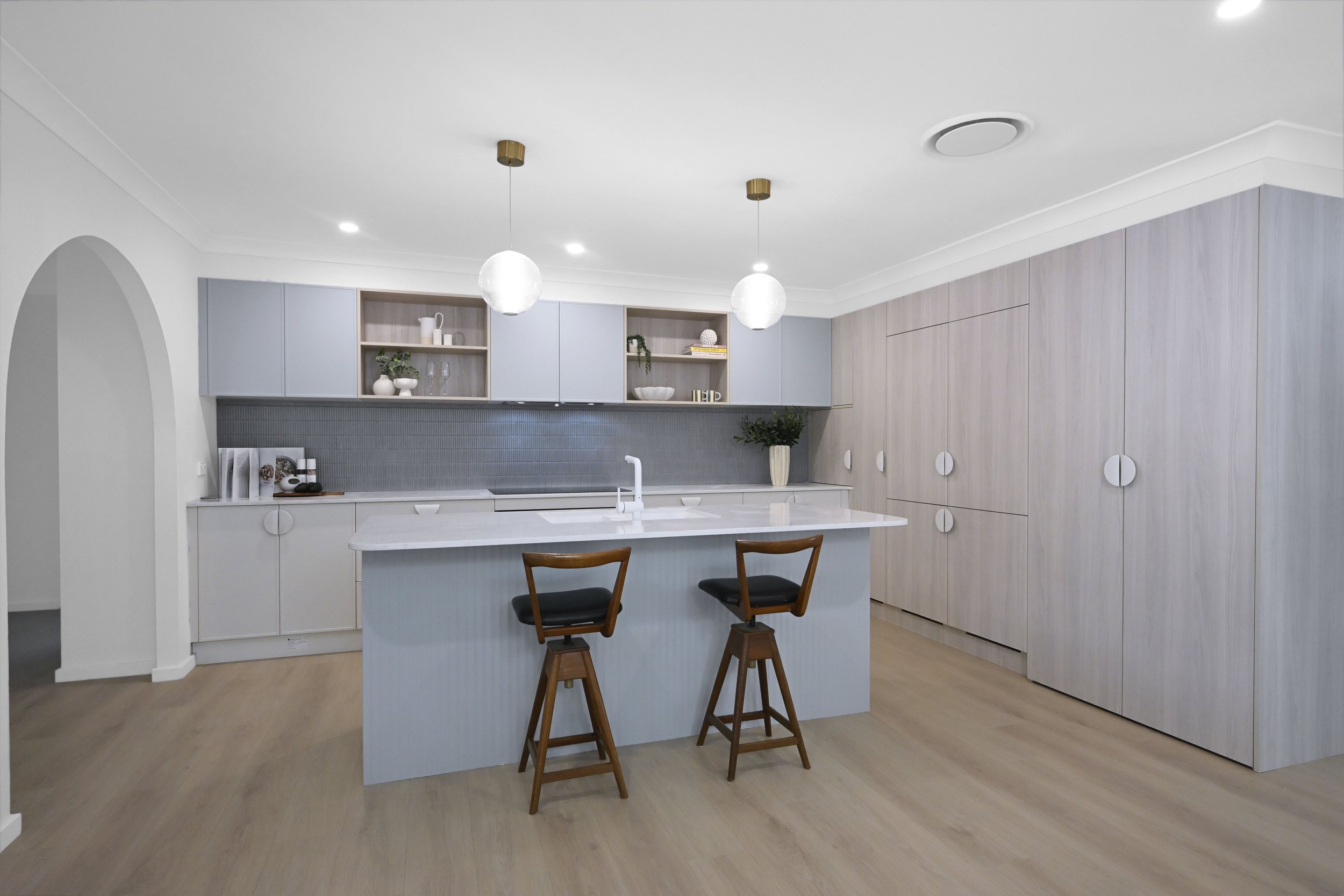 Open‑plan family kitchen with Caesarstone benchtops, soft cabinetry tones and integrated appliances
