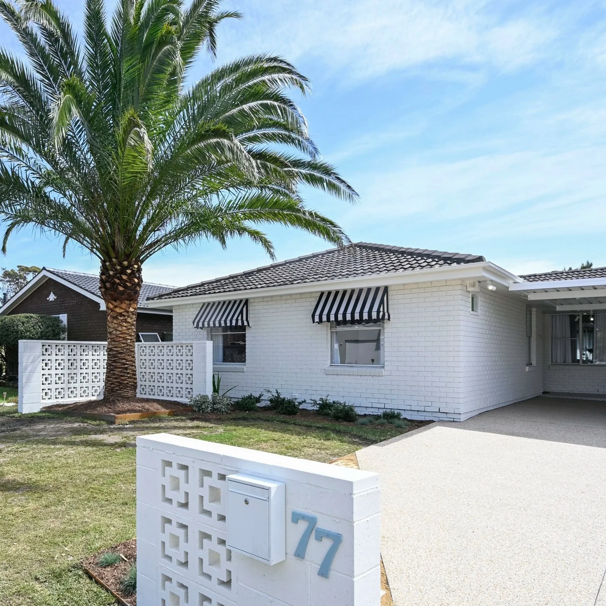Palm Springs–inspired façade with breeze blocks, crisp white paint, PebbleCrete driveway and signature canary palm