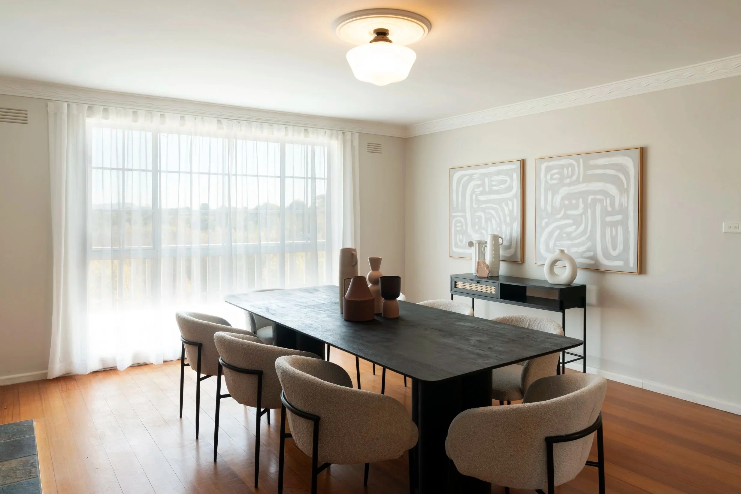 Spacious dining room with neutral palette, large table, open connection to living areas and garden views in Gisborne property.