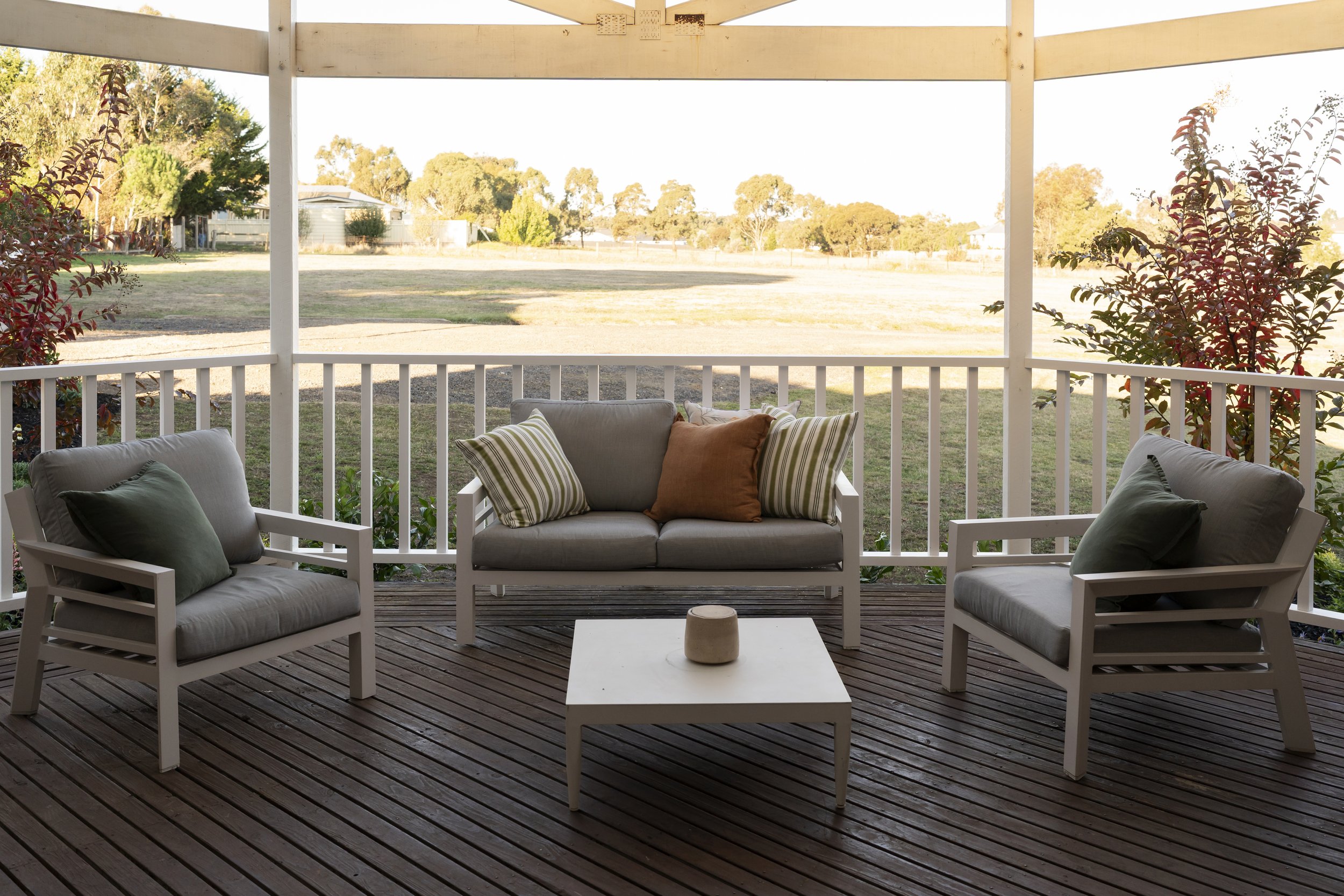 Front veranda with white balustrade, outdoor seating, soft neutral finishes and landscaped garden in Gisborne country property.