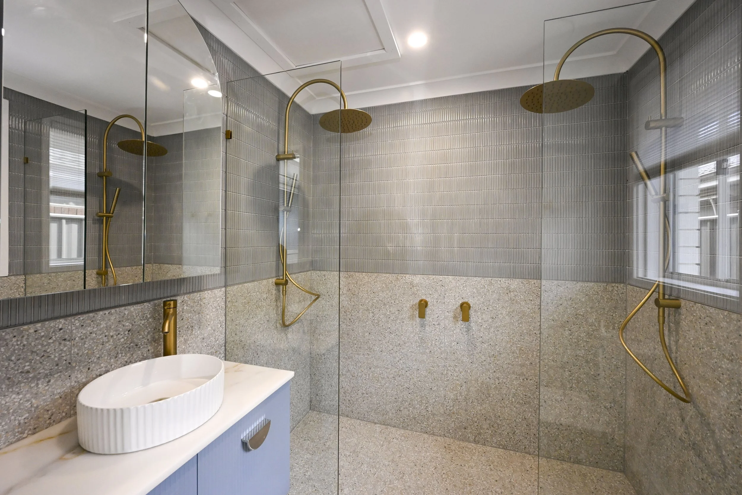 Soft blue vanity, brushed‑gold fixtures and bespoke mosaic feature wall.