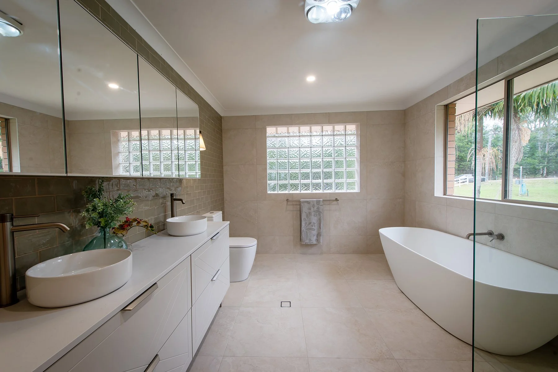 Spa‑style ensuite with freestanding bath, travertine tiles and brushed‑nickel fixtures.