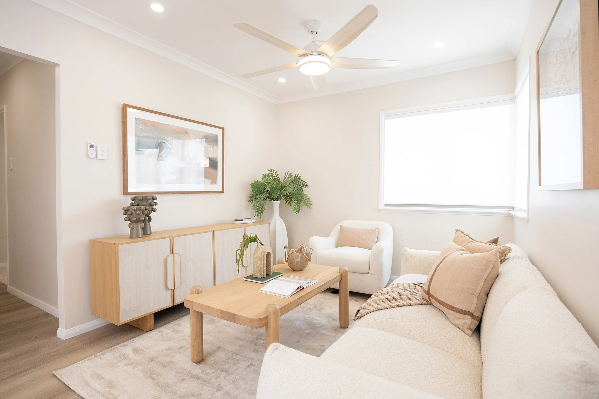 A light and bright renovated living room with couch, coffee table and buffet.
