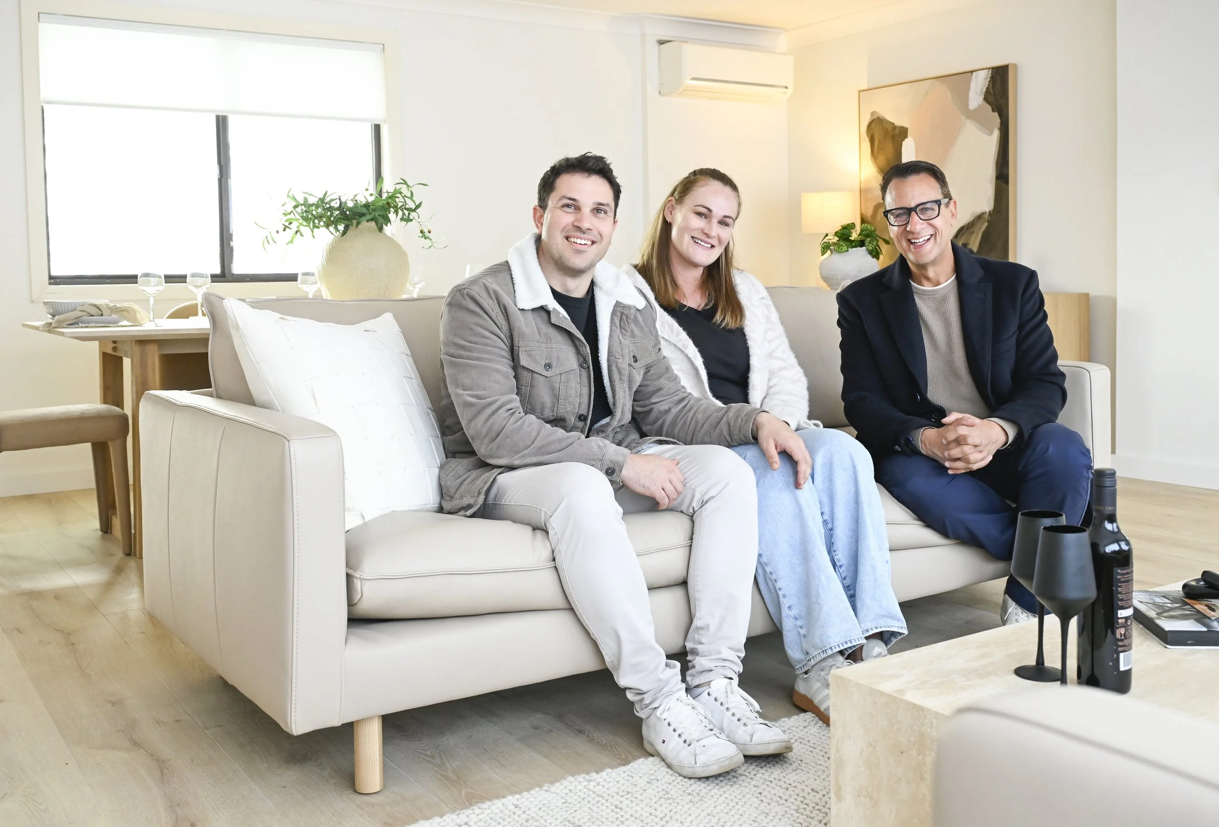 Smiling homeowners with Andrew Winter in a refreshed living room, light and bright.