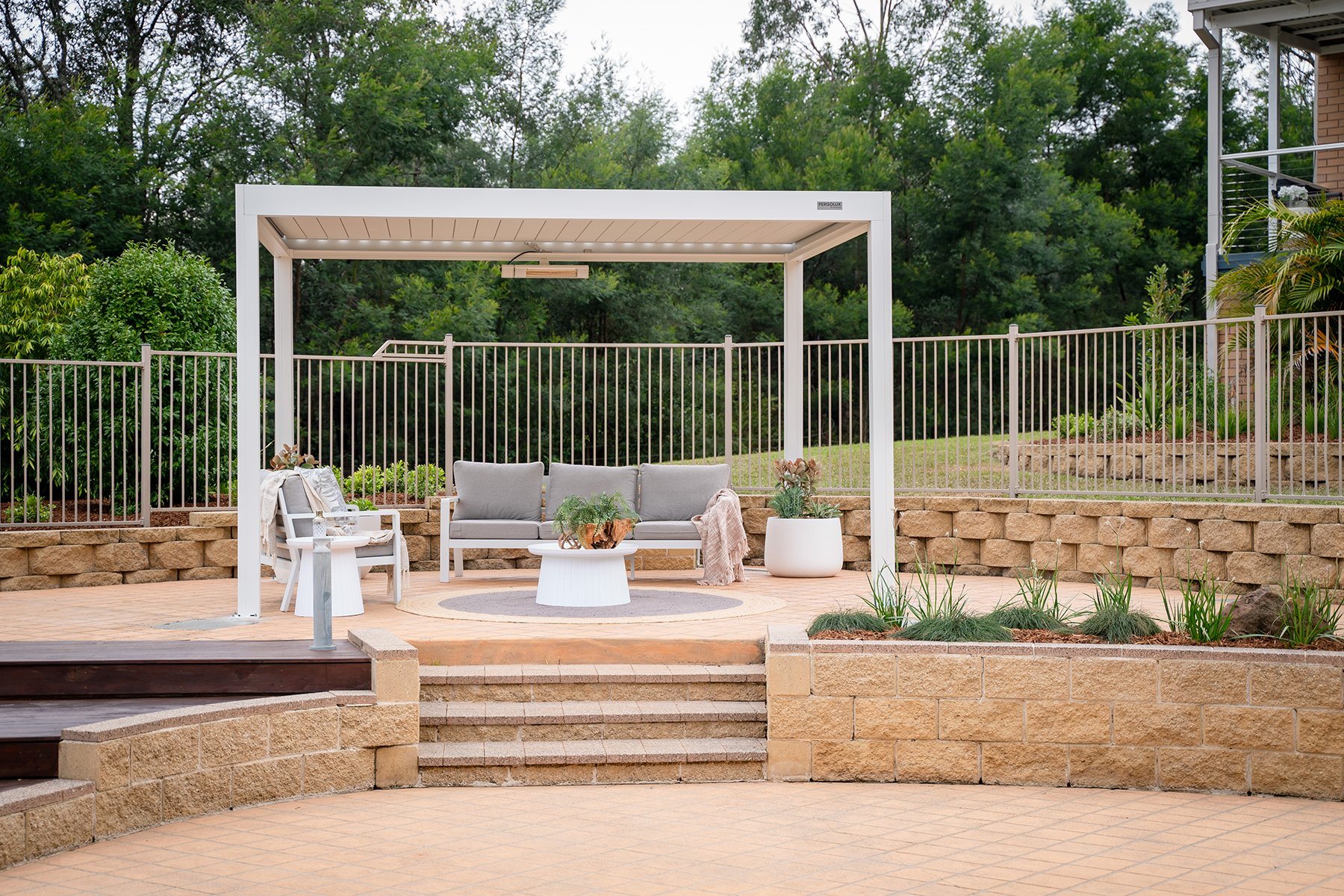 Modern pool zone with automated‑louvre pergola, fresh planting and oiled decking.