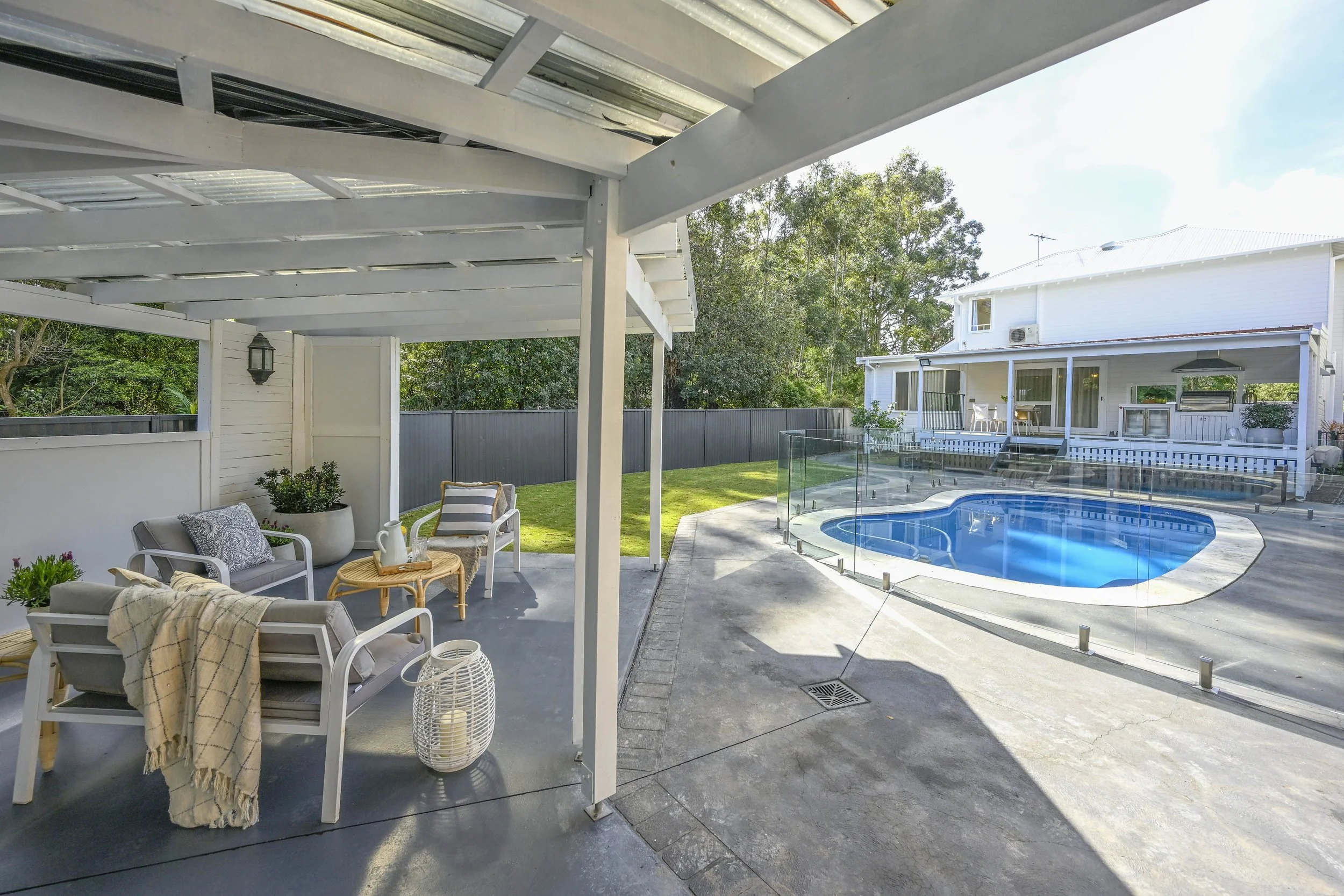 A Cape Cod style covered entertaining area, leading to a bright blue pool and barbecue zone.