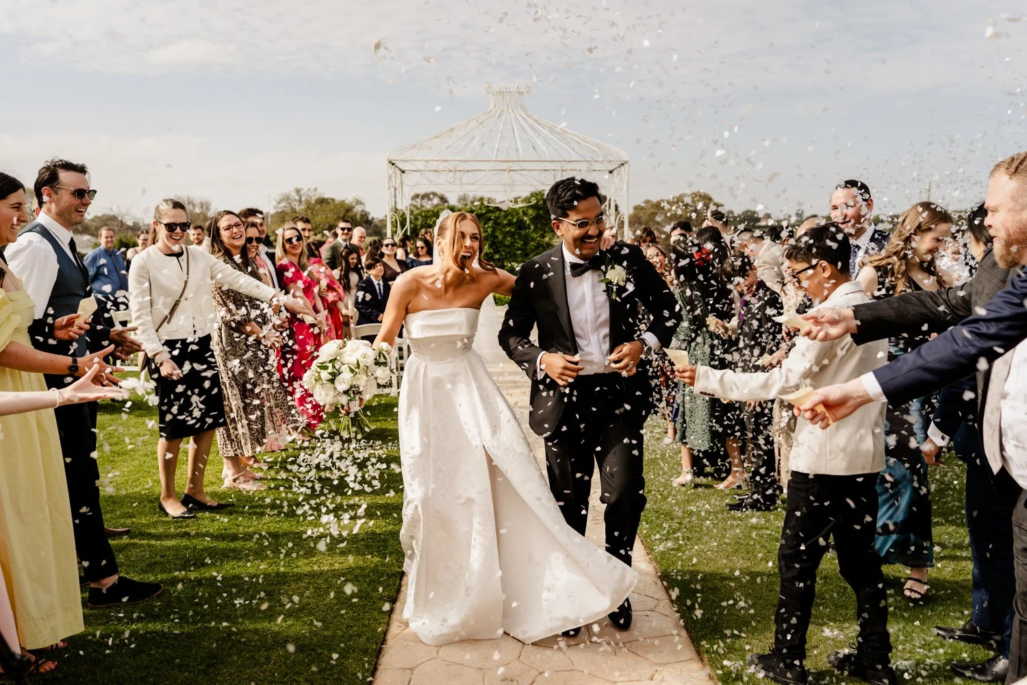 bride and groom showered by confetti as they walk down the aisle