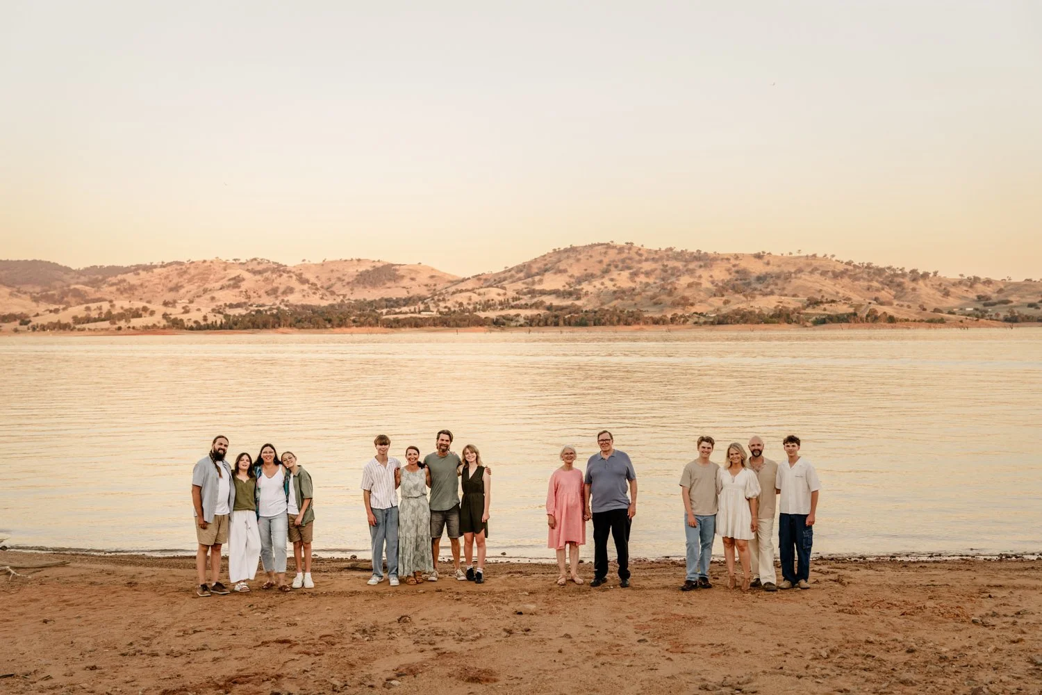 extended family stands together at sunset by the lake