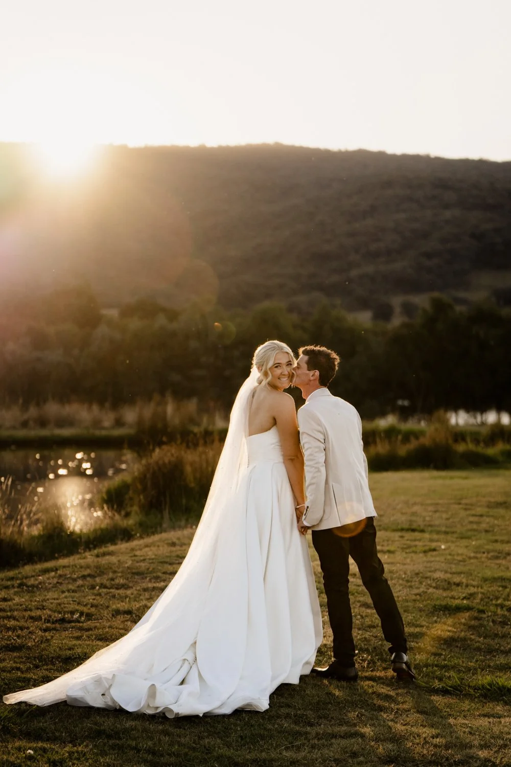 sunset wedding at location. Groom kissing bride