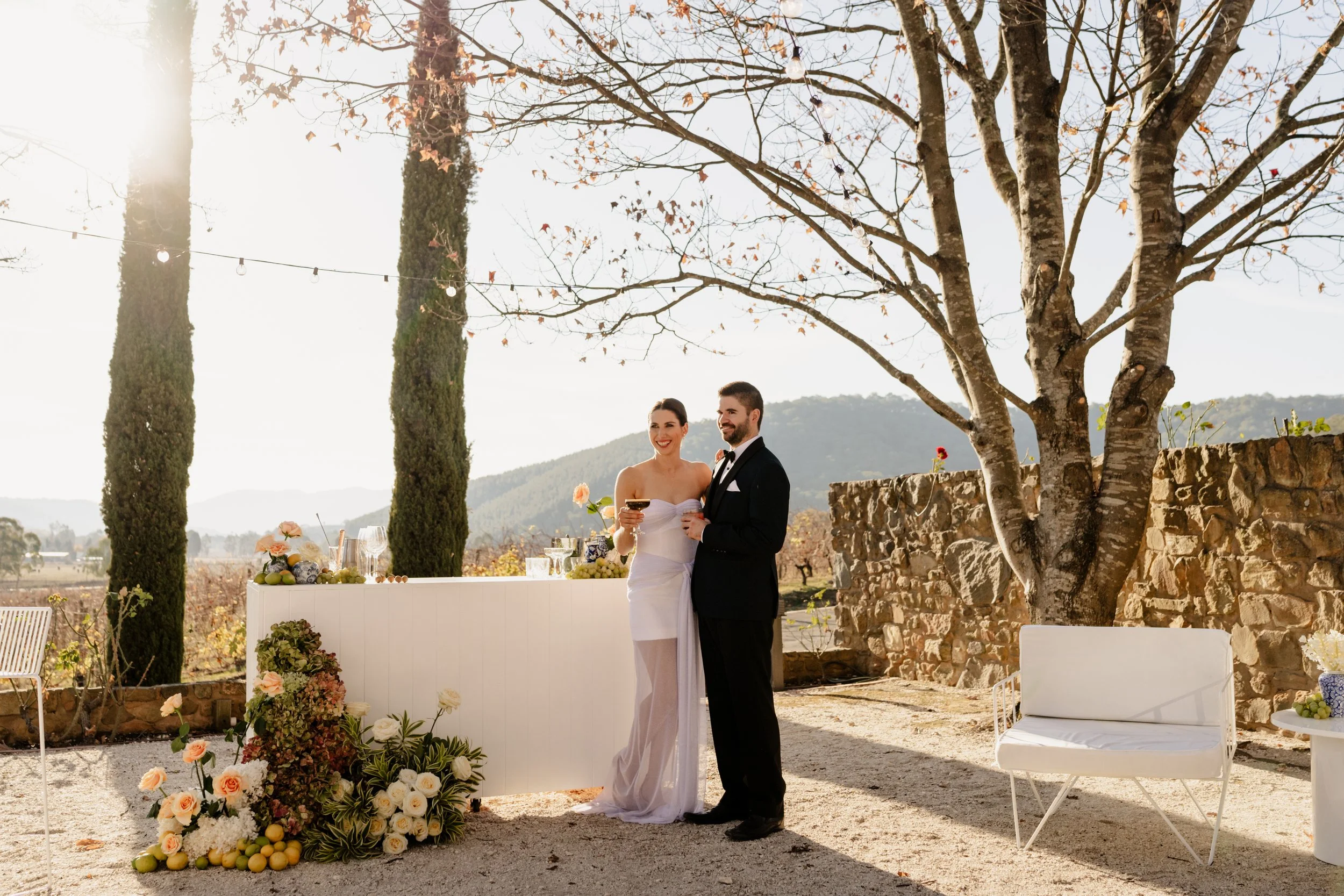 Bride and groom sipping cocktails at sunset