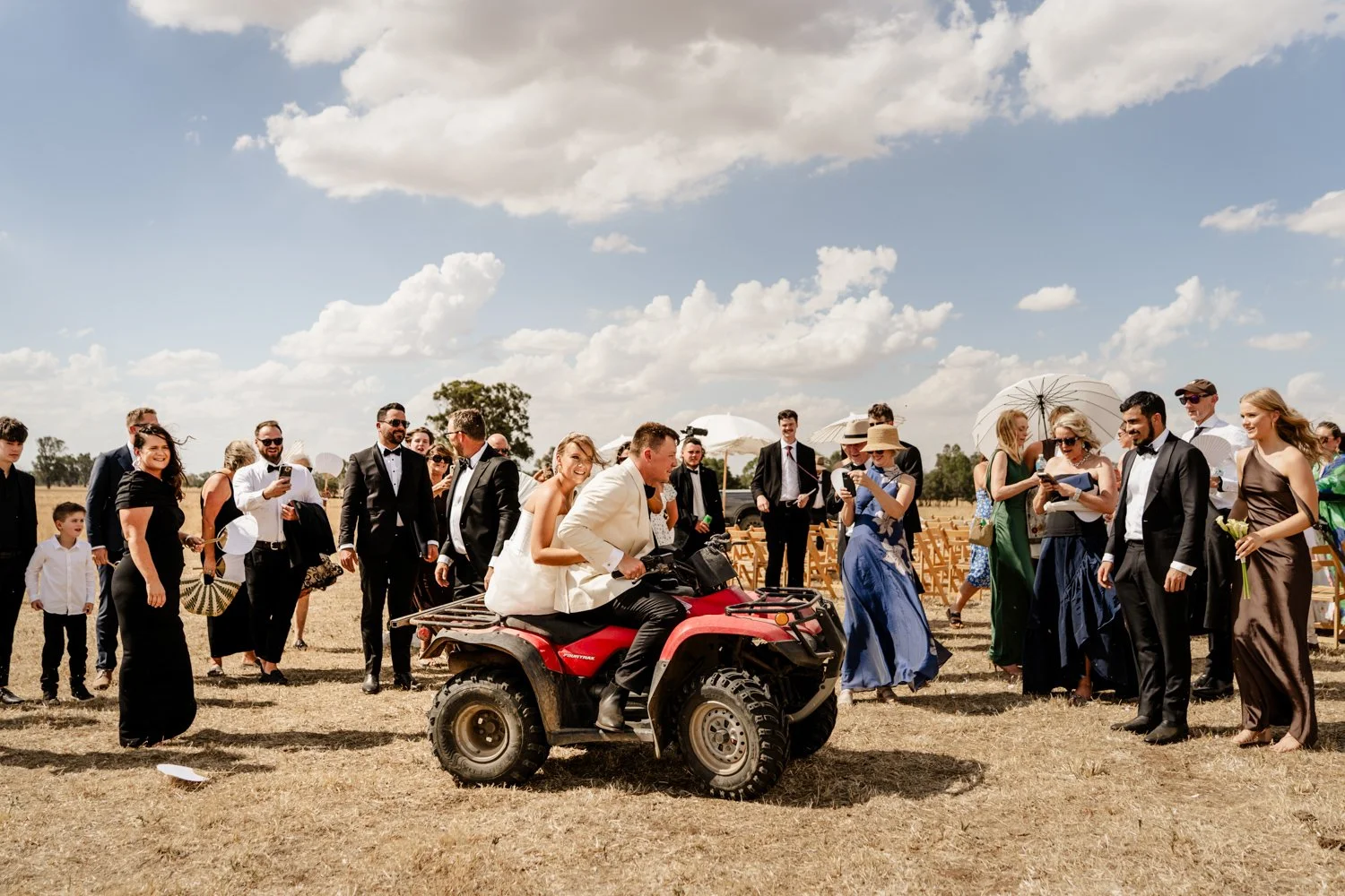 newly married couple drive away on the back of a motorbike