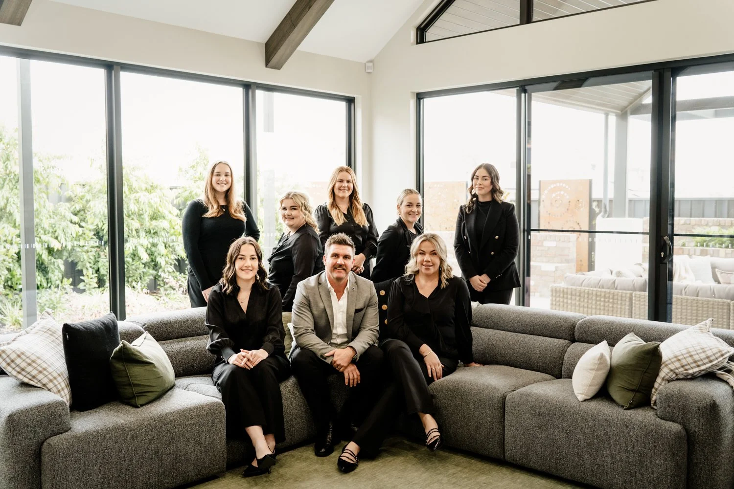 real estate team sit together on the couch looking at the camera