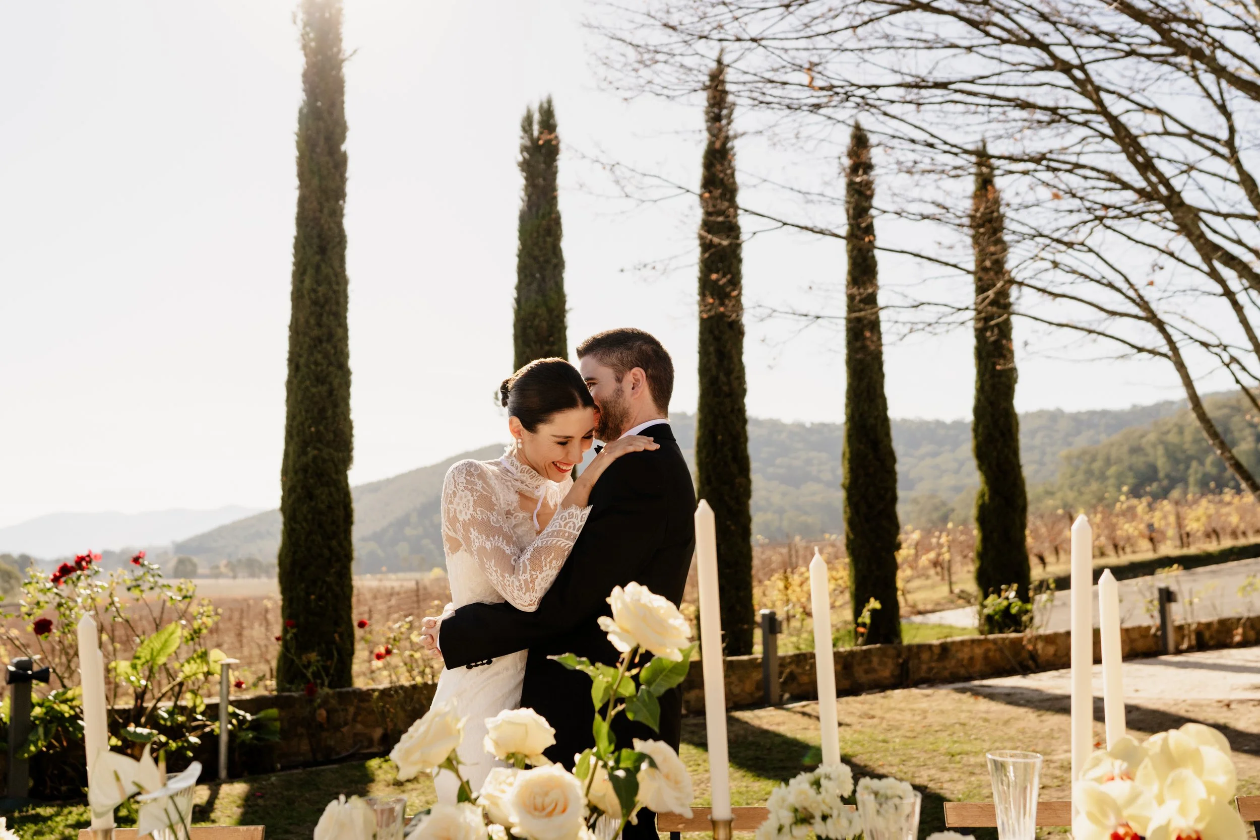 Bride and groom hugging in front of table outside