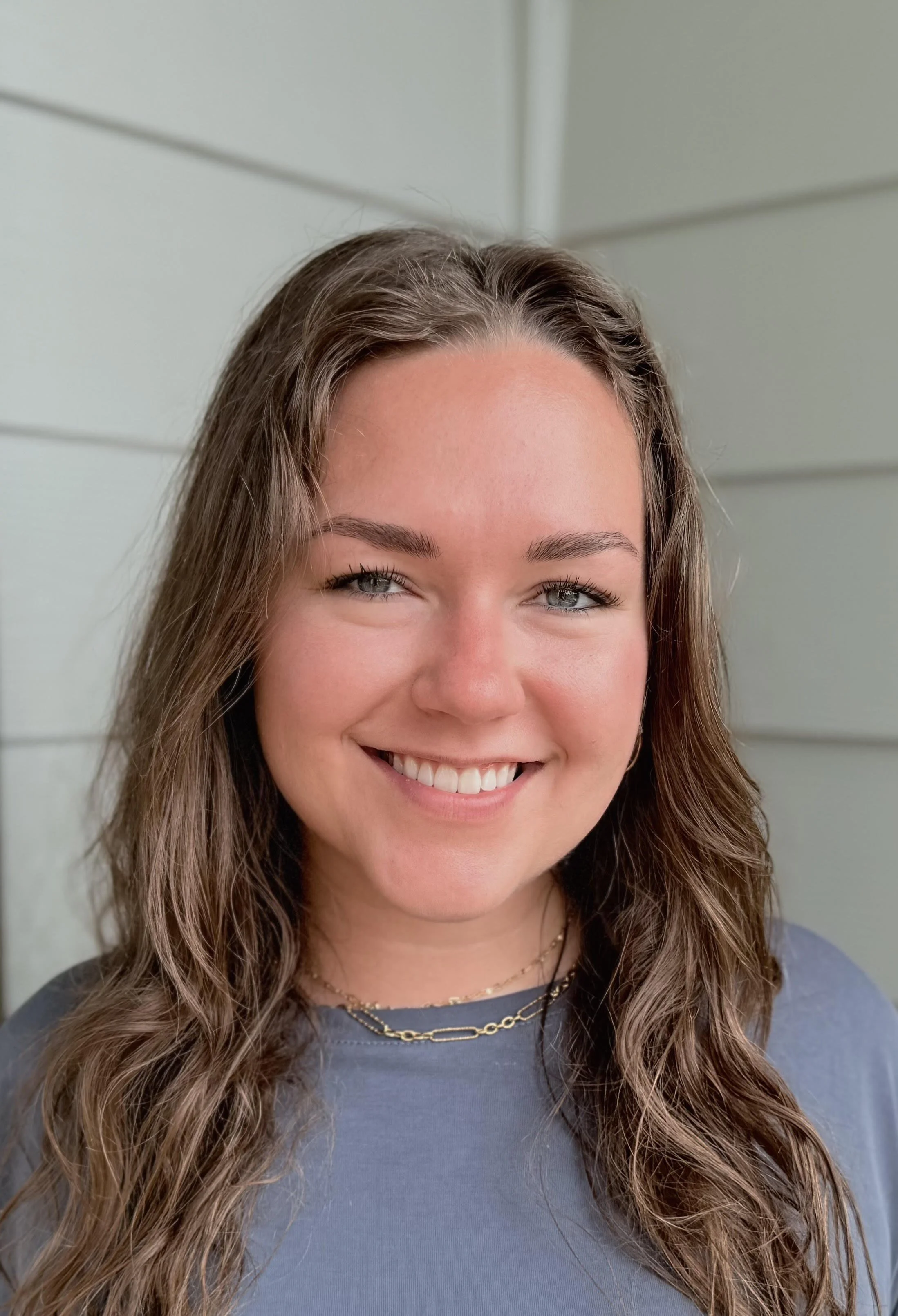 Woman taking a selfie on a snowy forest trail with trees and steps in the background.