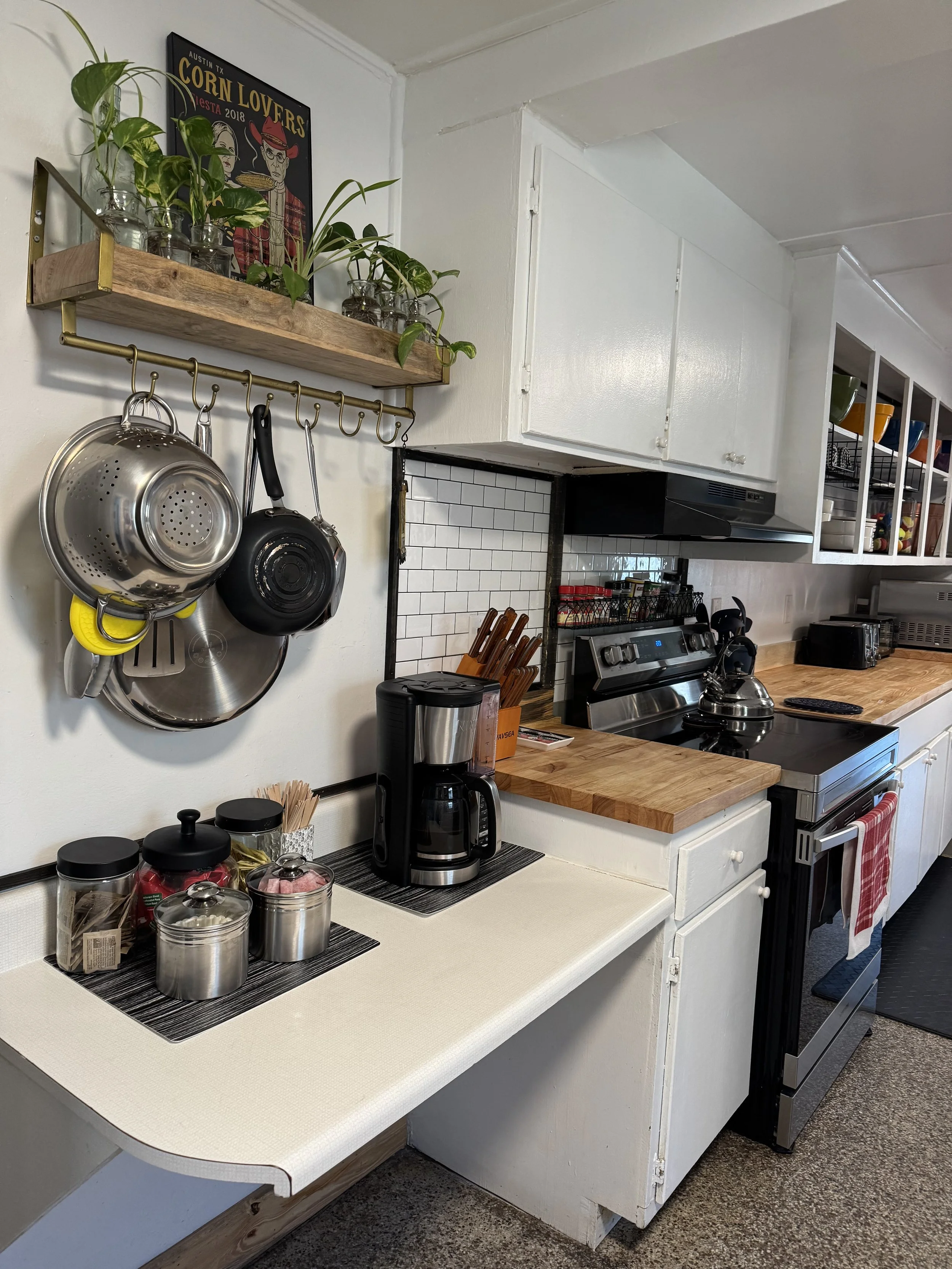 Kitchen with hanging pots and pans, a coffee maker, a wooden countertop, and various kitchen utensils and appliances.