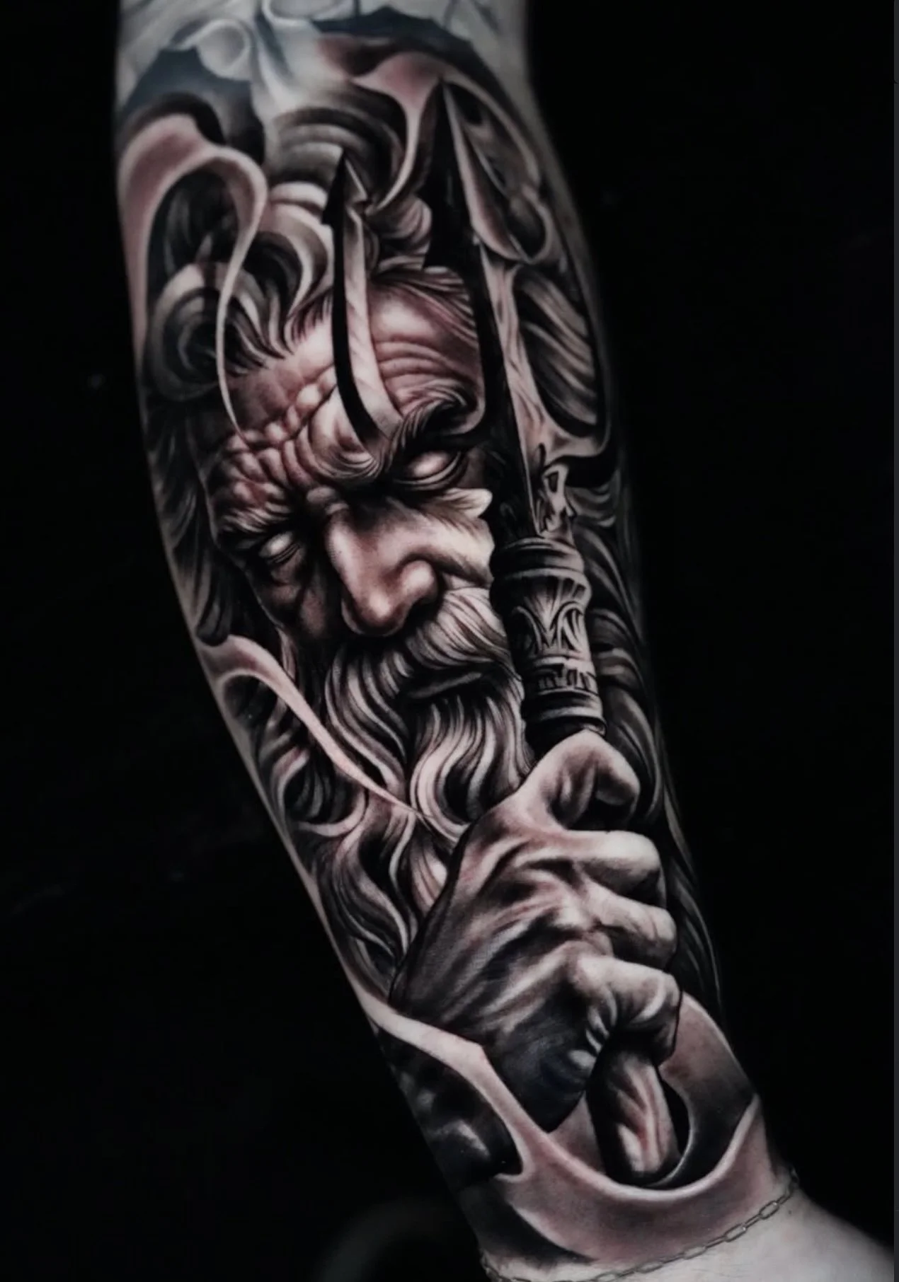 A black and gray realistic tattoo of an elderly man with a long beard, holding a pipe to his mouth, covering the entire forearm.