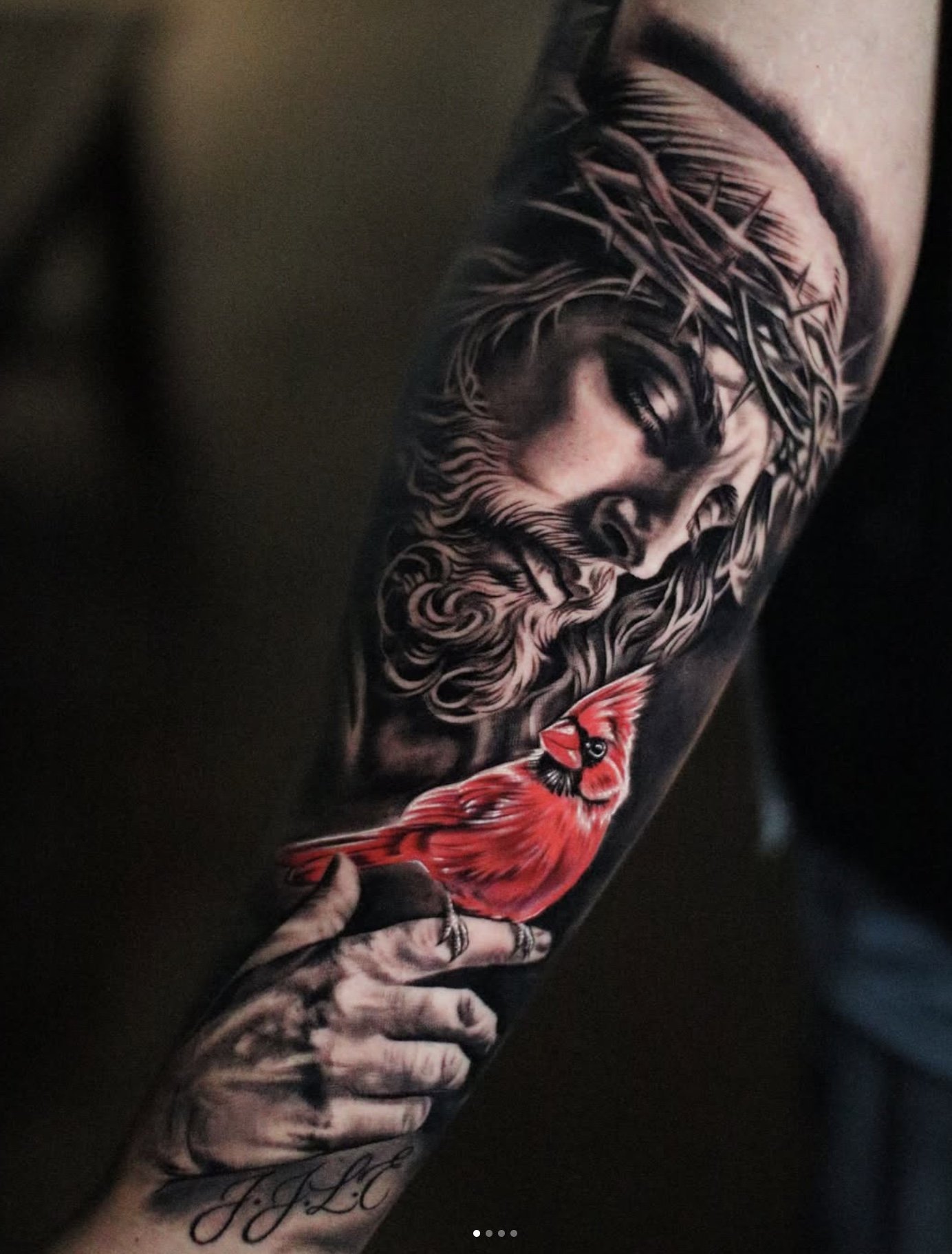 Tattoo of a woman's face with long hair and a crown of thorns, holding a red cardinal bird with a detailed hand.