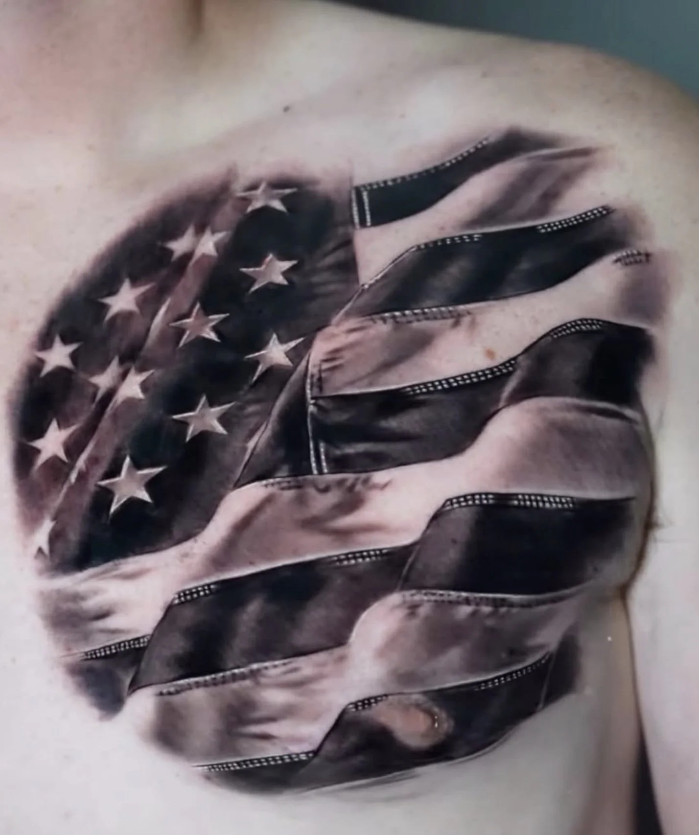 Close-up of a person wearing a leather jacket with an American flag pattern, featuring stars and stripes, lying on a flat surface.