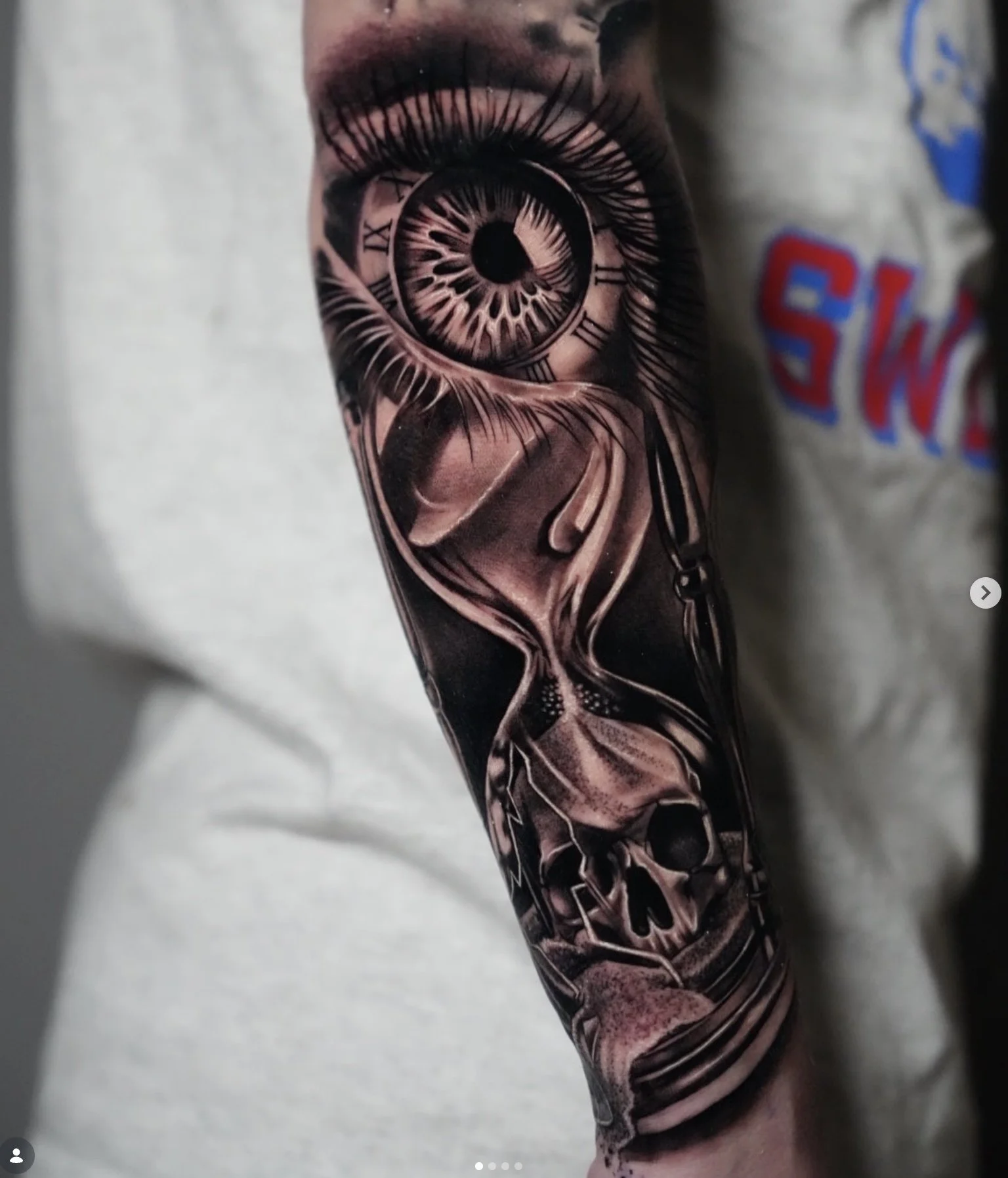 Tattoo of a detailed eye with a clock face in the iris on a person's arm, with realistic shading and intricate lines.